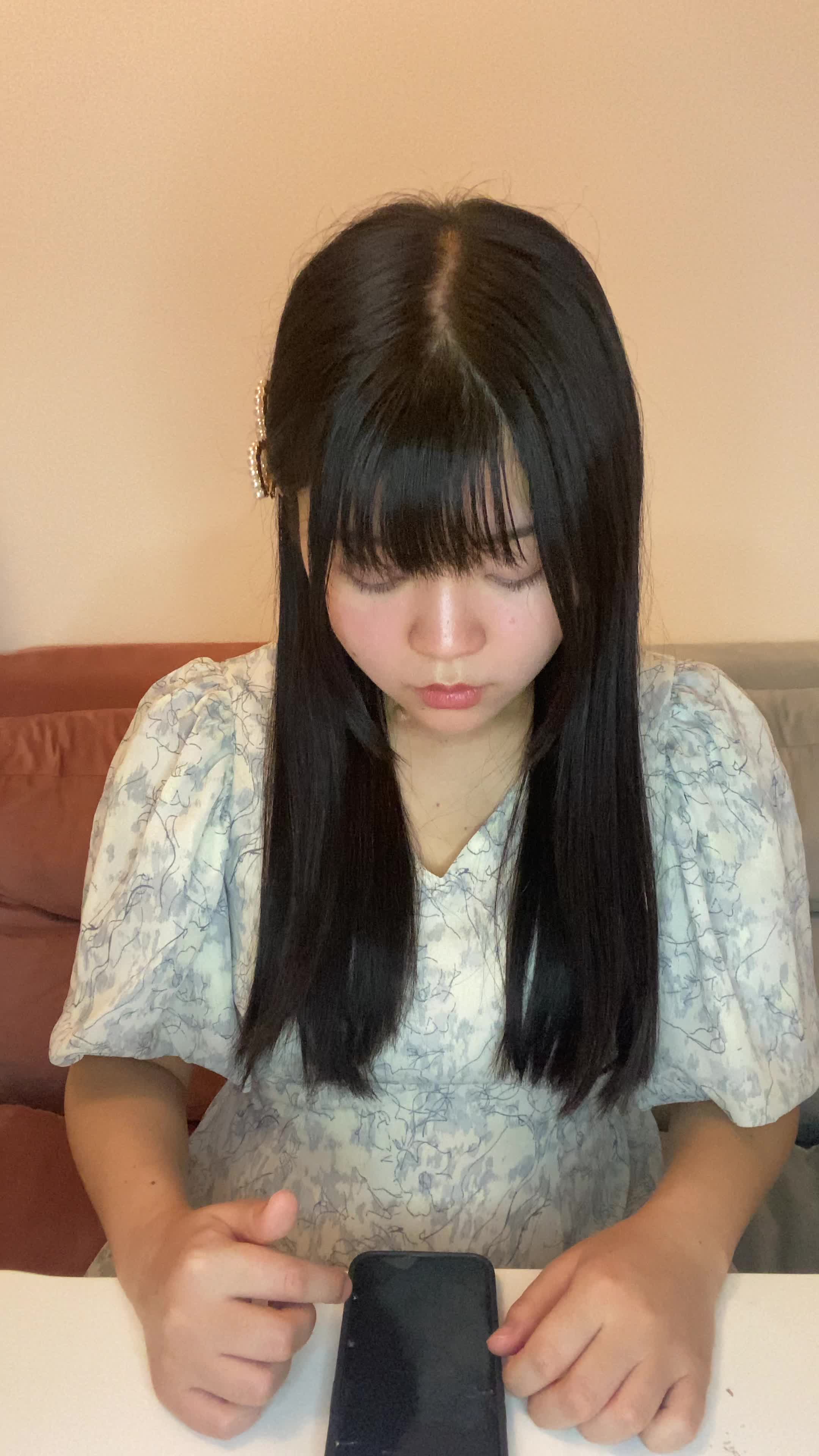 テーブルに置いたスマホの画面を見て、「サロン帰りの髪が自宅でも再現できる？」と期待する表情