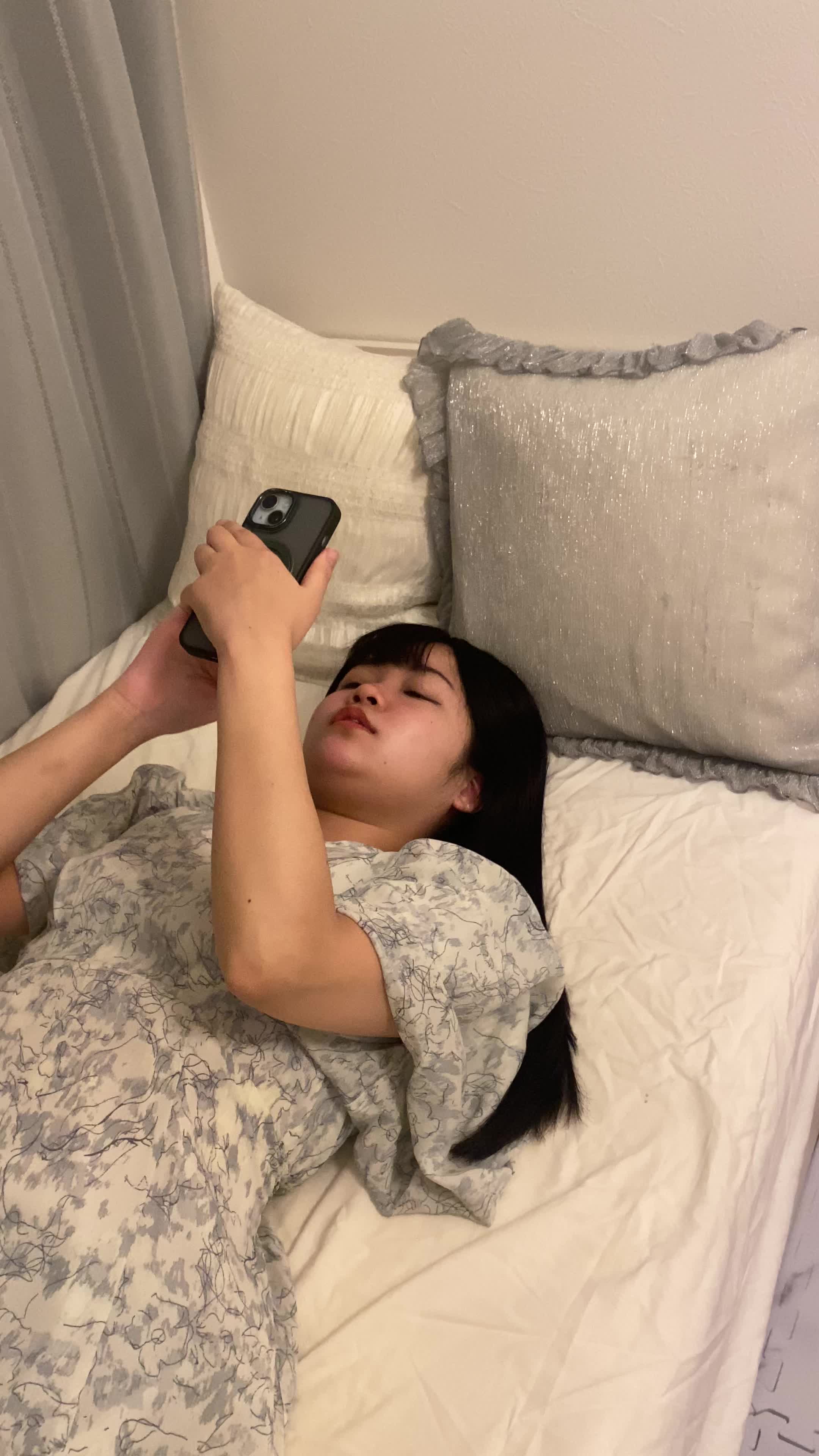 ベッドで横になり、スマホで「髪をサラサラにする方法」を検索している姿