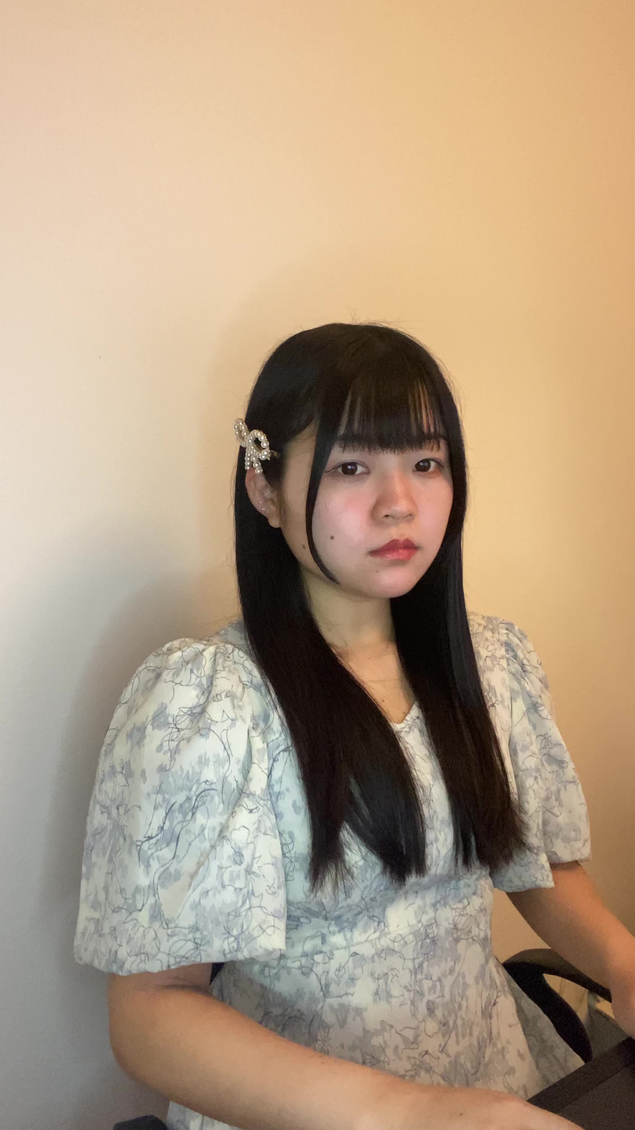 椅子に座り、仕事中に髪のパサつきが気になり、少しイライラする表情を見せる姿