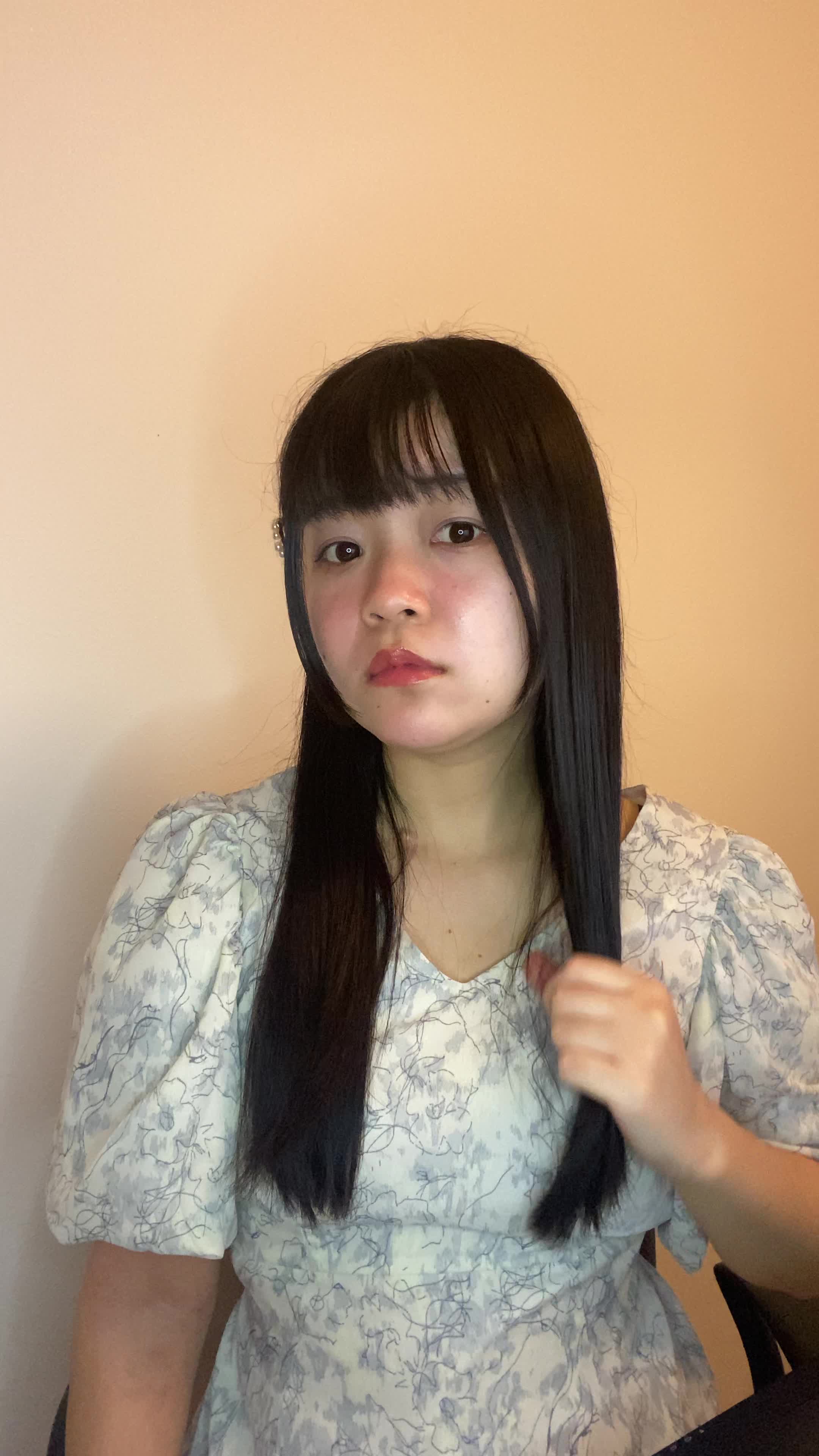 椅子に浅く腰掛け、髪を手ぐしで整えながら「このシャンプー試してみよう」と決意する表情