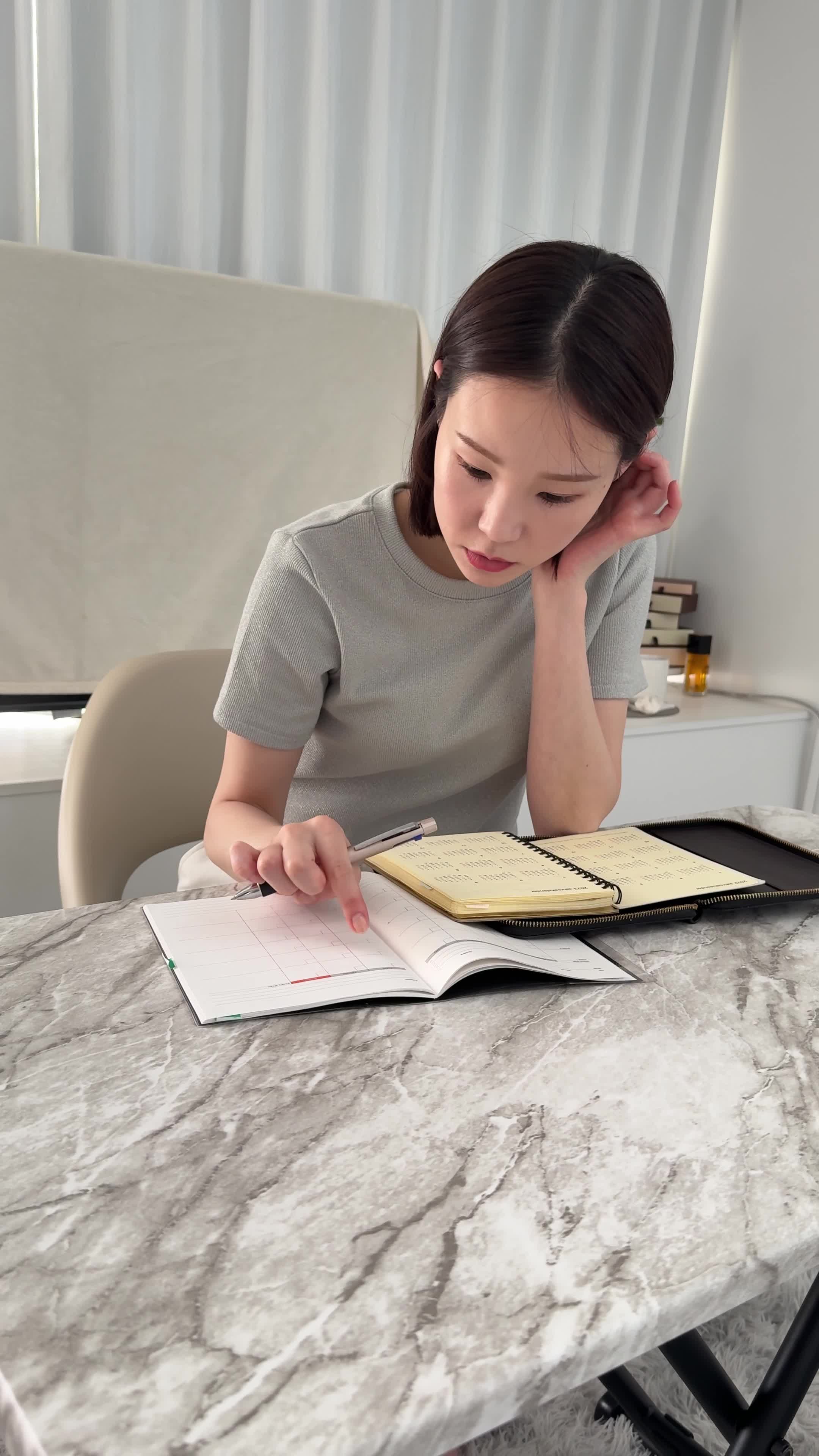 テーブルで手帳を開き、「応募の締め切りを確認する」集中した姿