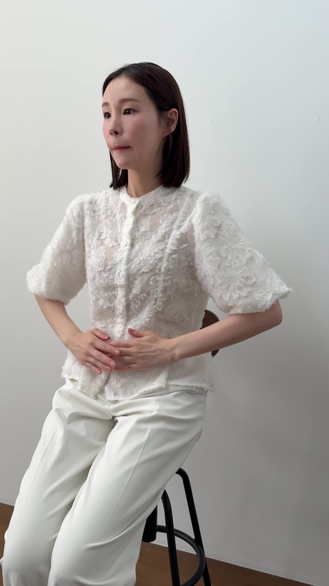 椅子に浅く腰掛け、「下腹部を両手で押さえて痛みを和らげようとする」動作