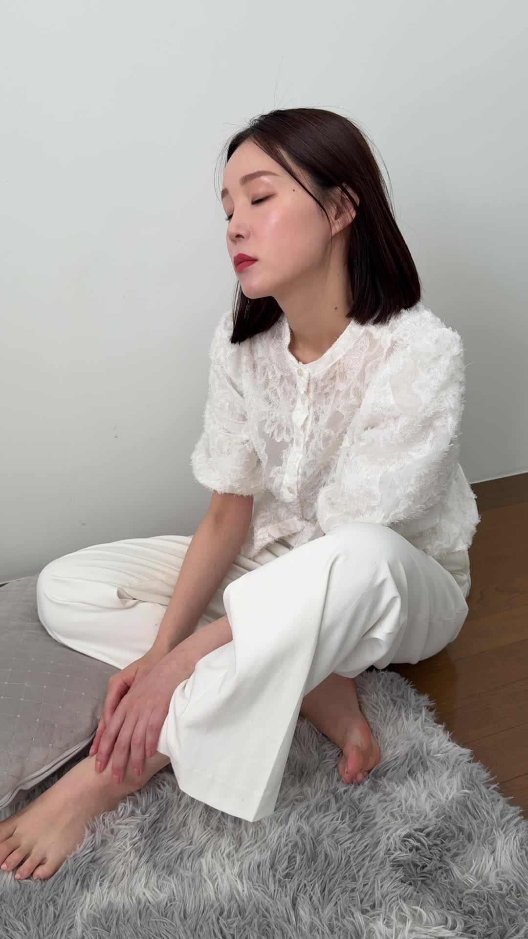 床で膝を崩して座り、「お腹の痛みで集中できない」と悩む真剣な表情
