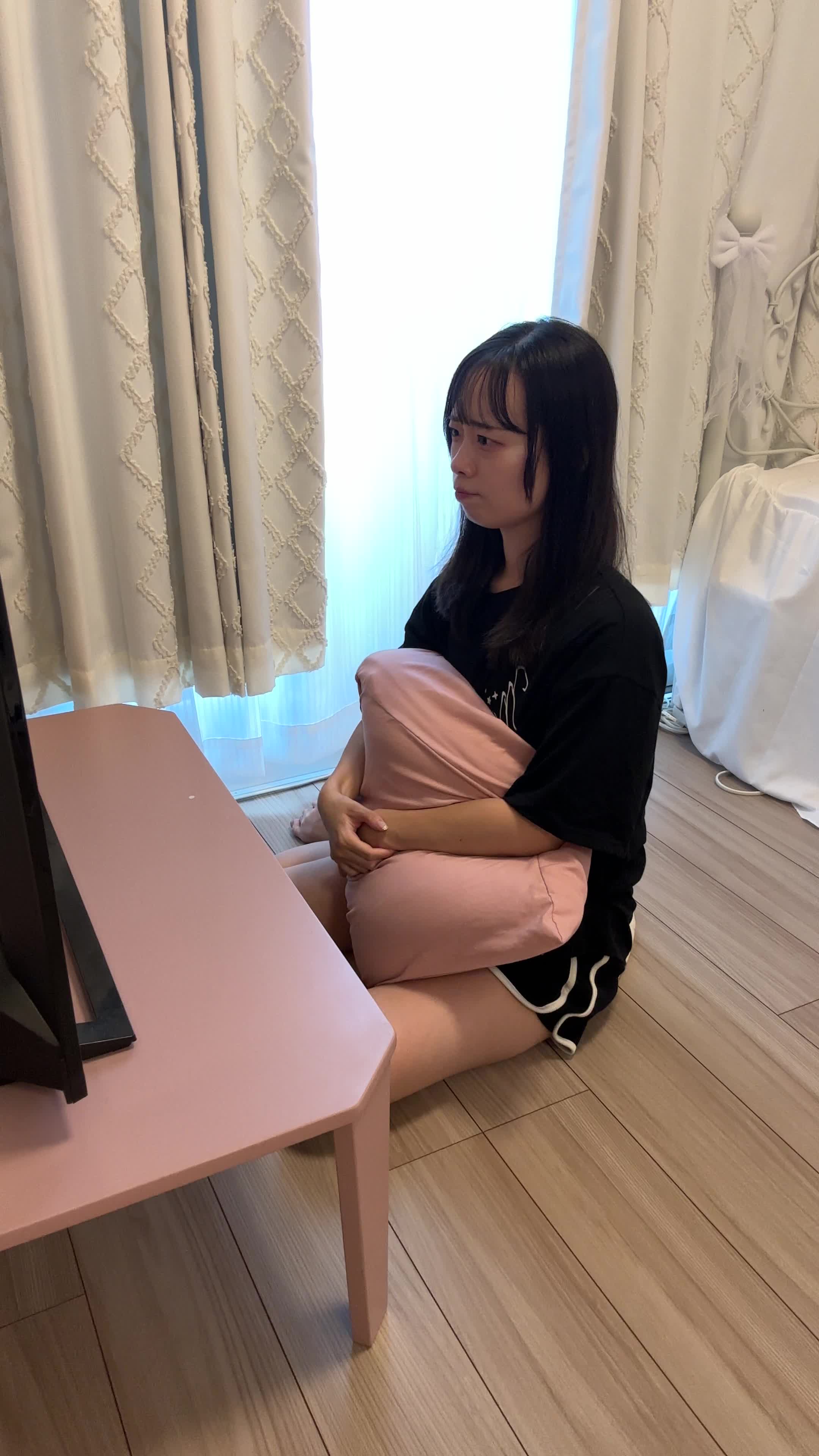 ソファでクッションを抱きながら、「あと少しで勝てる！」と真剣な表情を見せる動作