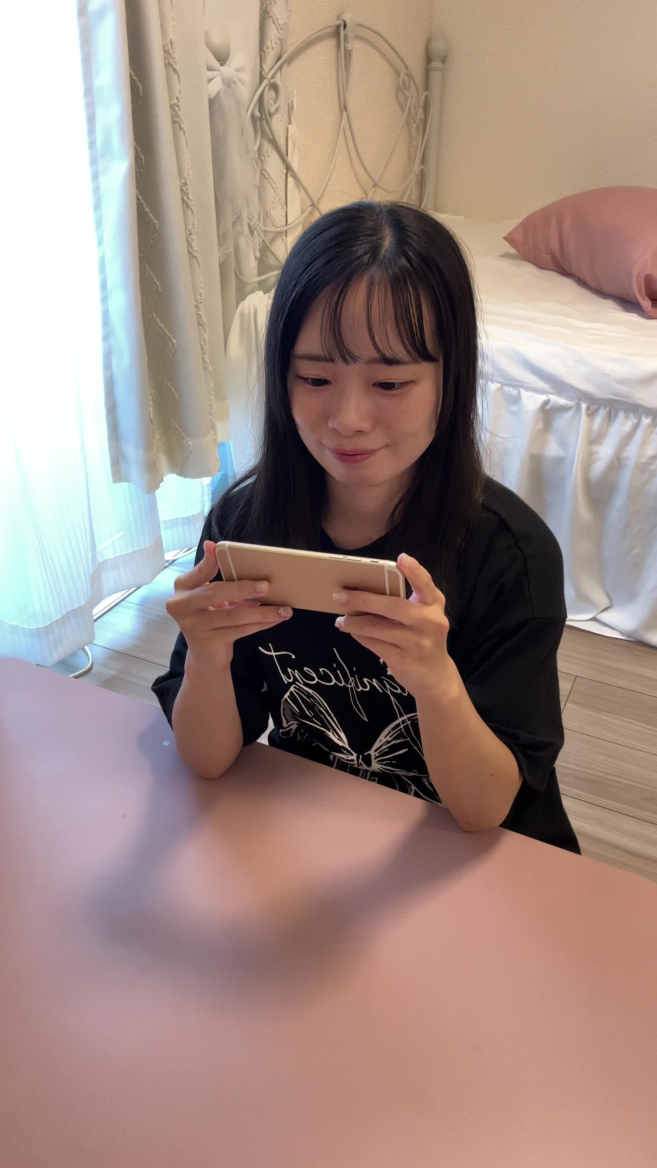 テーブルに肘をつき、スマホゲームを操作しながら「やった！」と喜びを爆発させる様子