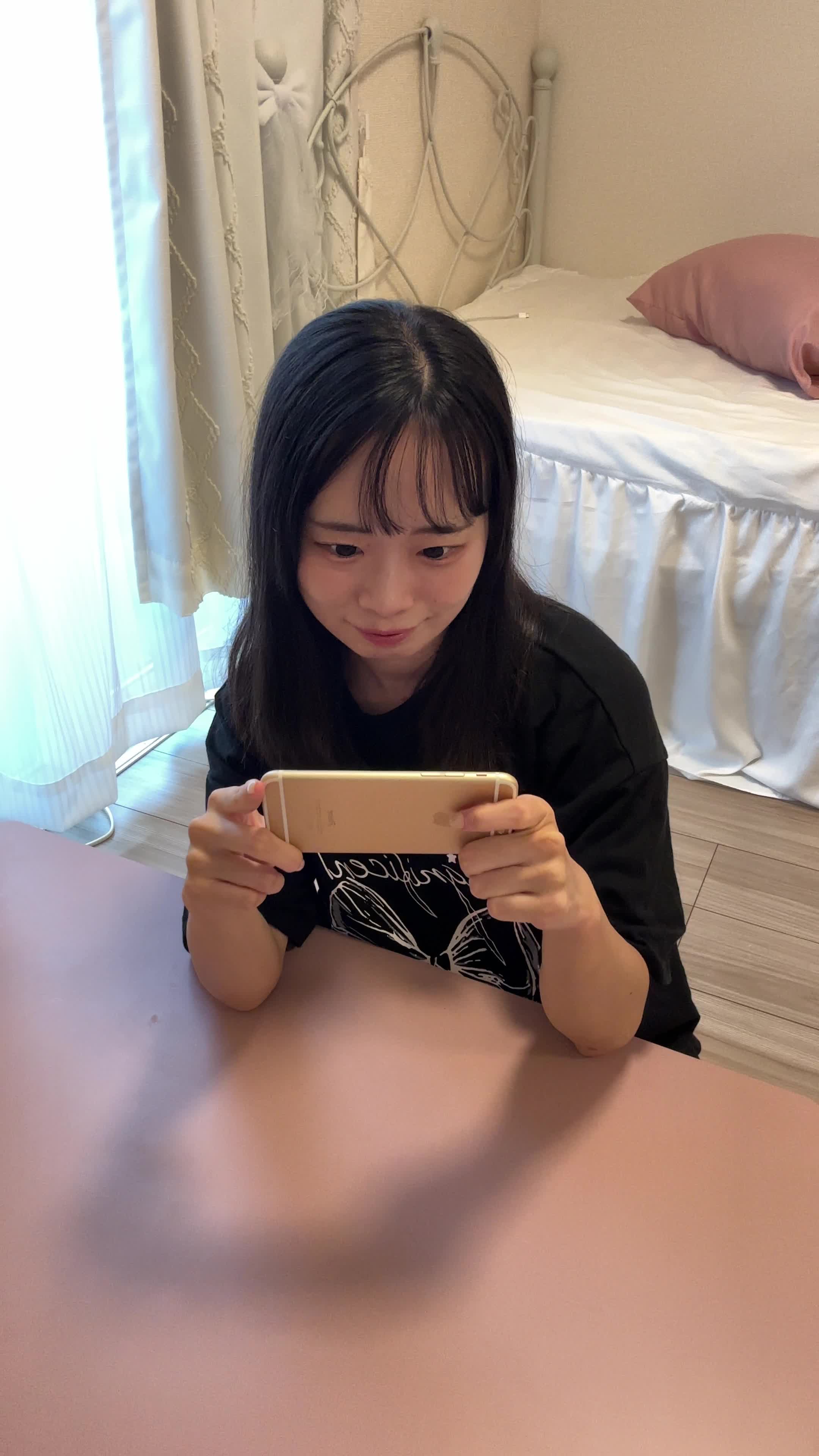 テーブルでスマホゲームの結果画面を見て、両手を上げてガッツポーズをする動作