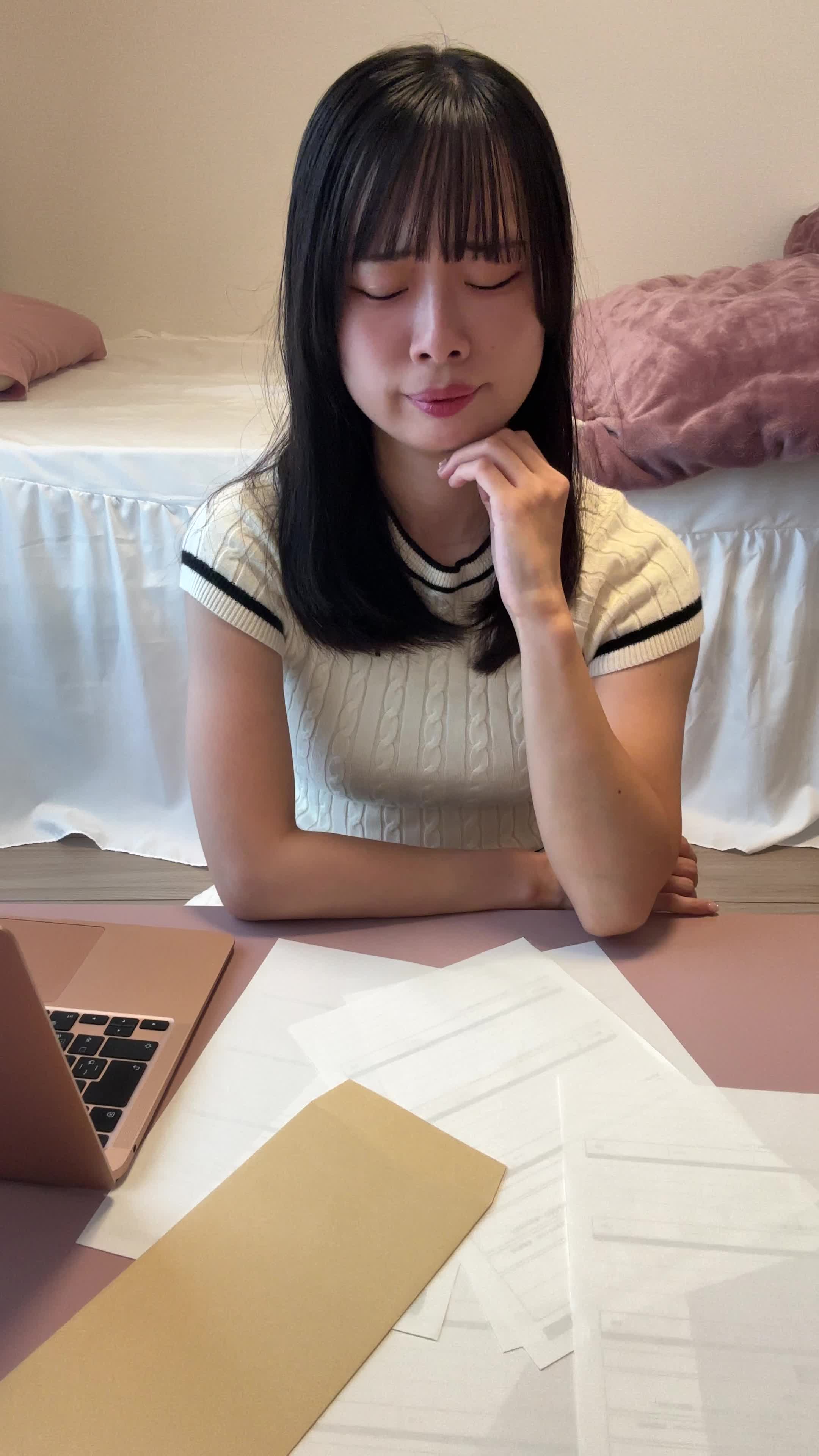 椅子に座り、テーブルに書類を広げて「どうしよう」と悩む真剣な表情