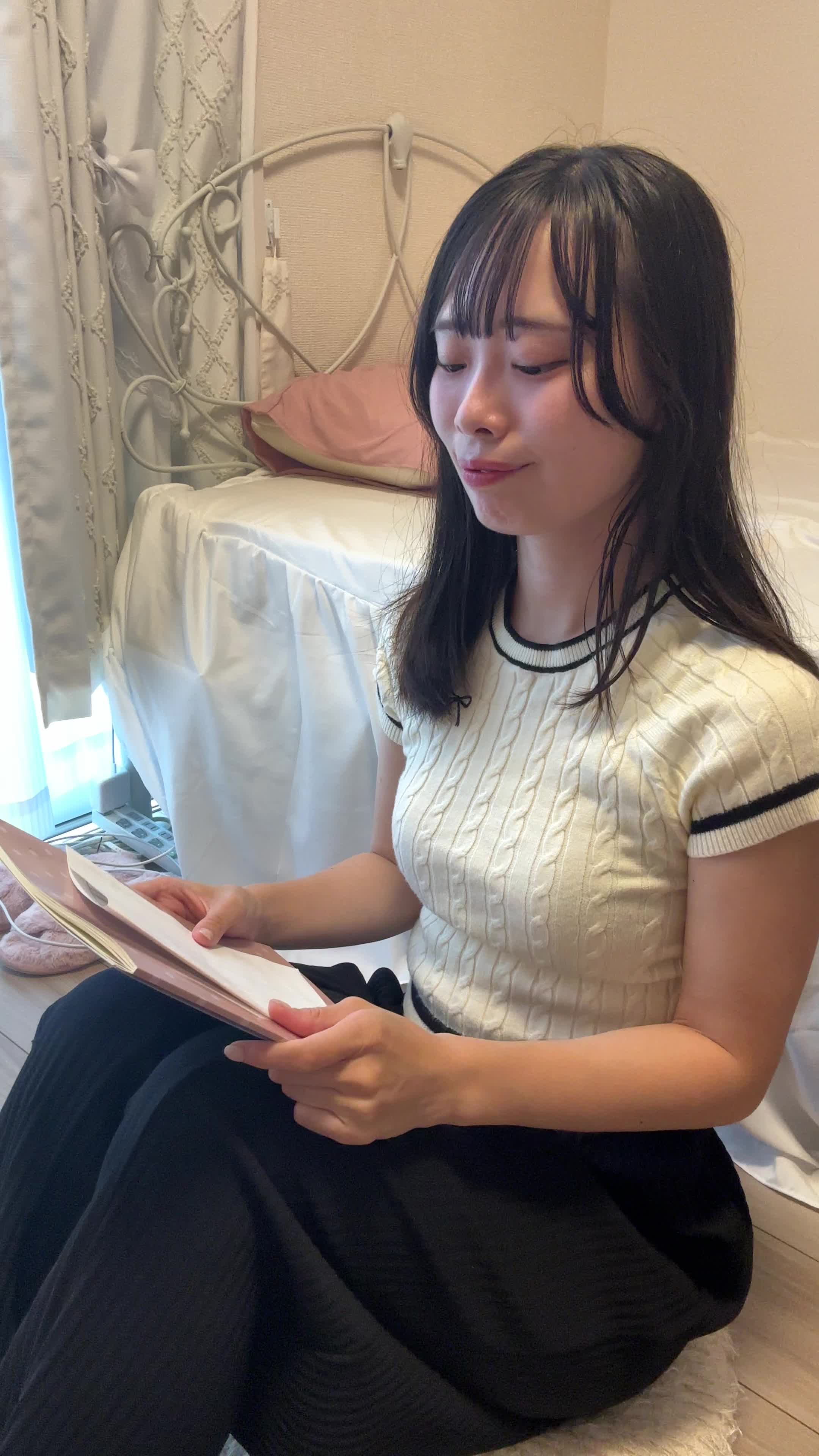 床に座り込み、資料を見つめて「これで解決するのかな」と希望を見出す表情