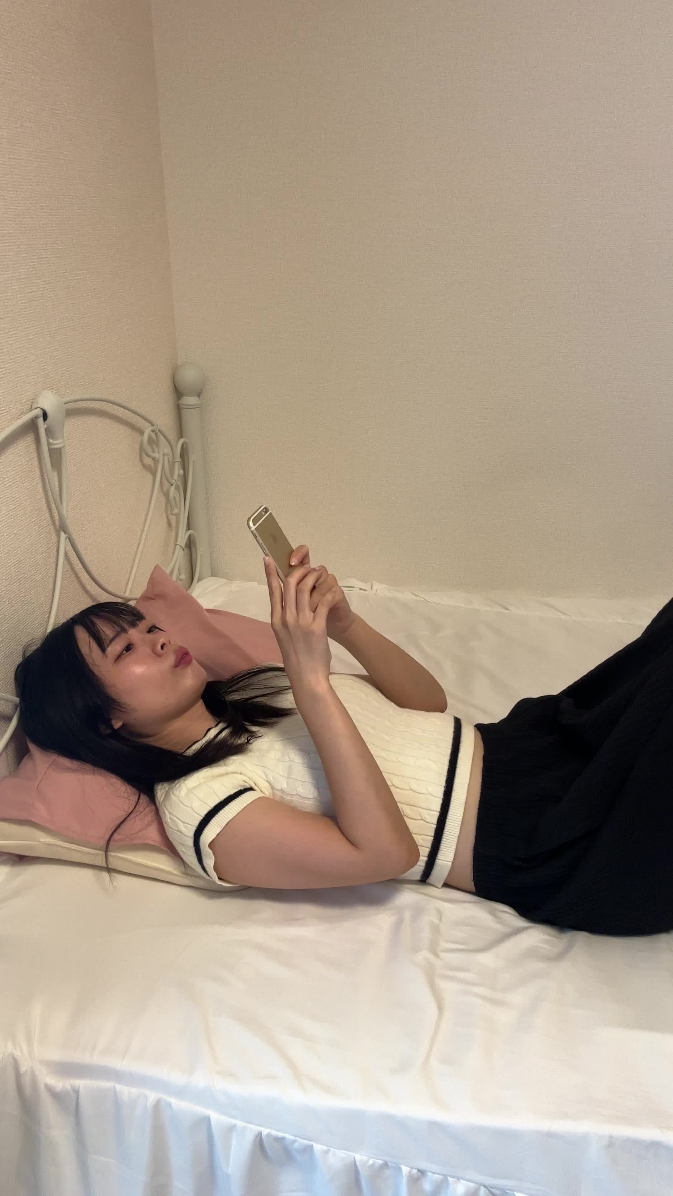 ベッドで横になり、スマホで「債務整理の口コミ」をチェックする集中した様子