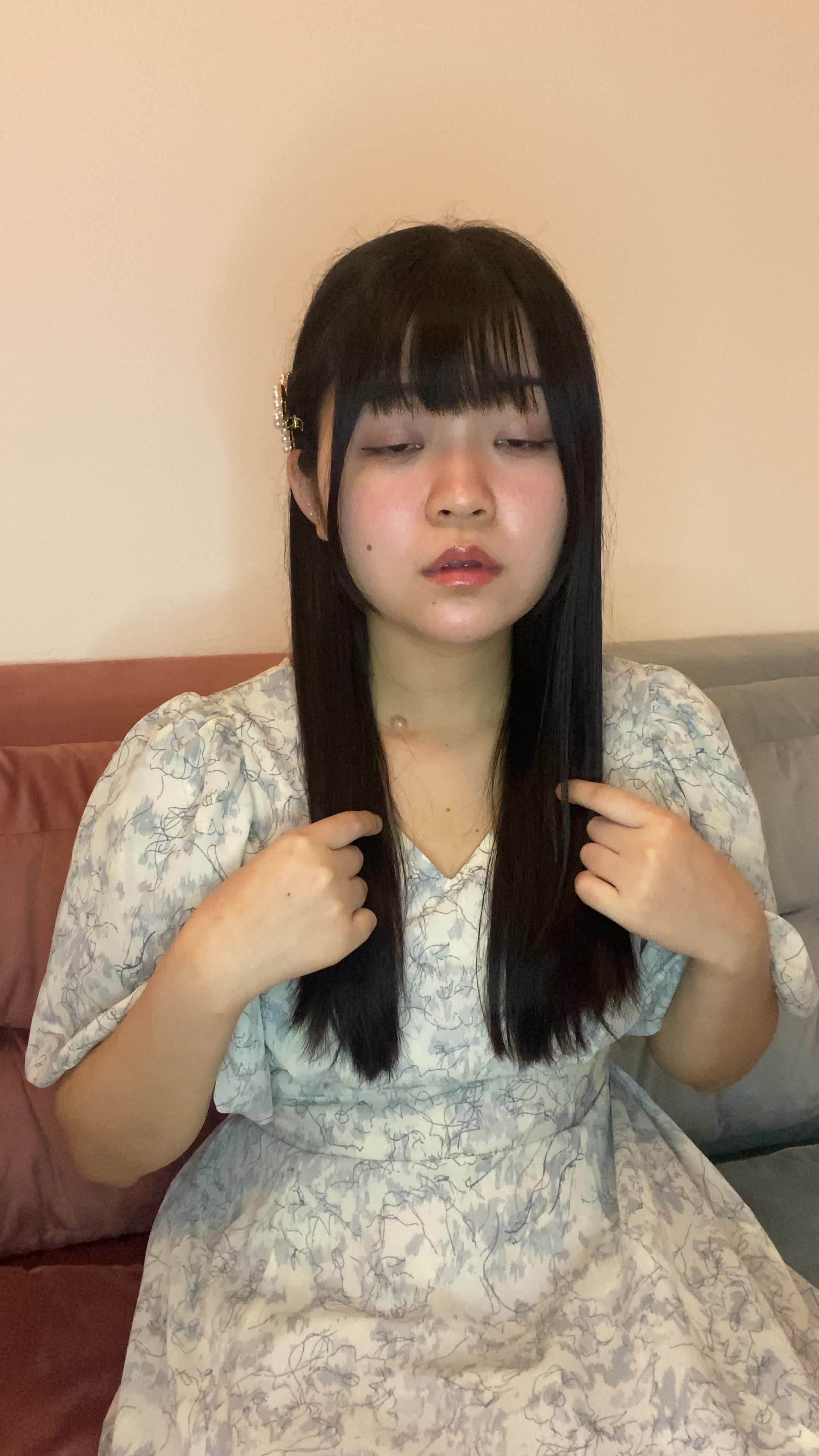 ソファで友達に髪のパサつきを指摘され、軽く傷ついた表情を浮かべる様子