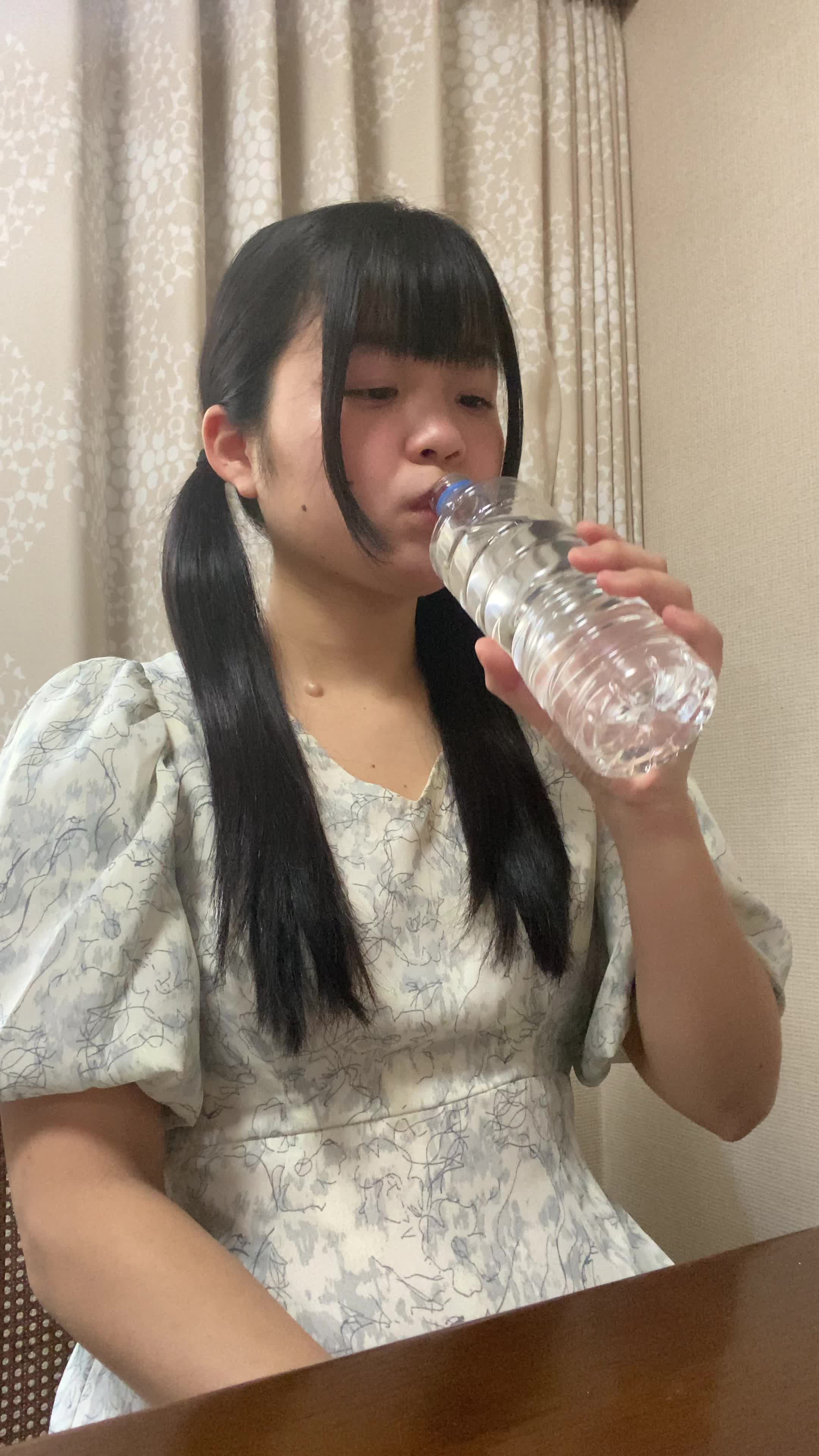 椅子に座り、ペットボトルの水を飲みながら「もっと手軽に冷たい水が飲めたらいいのに」と考える表情