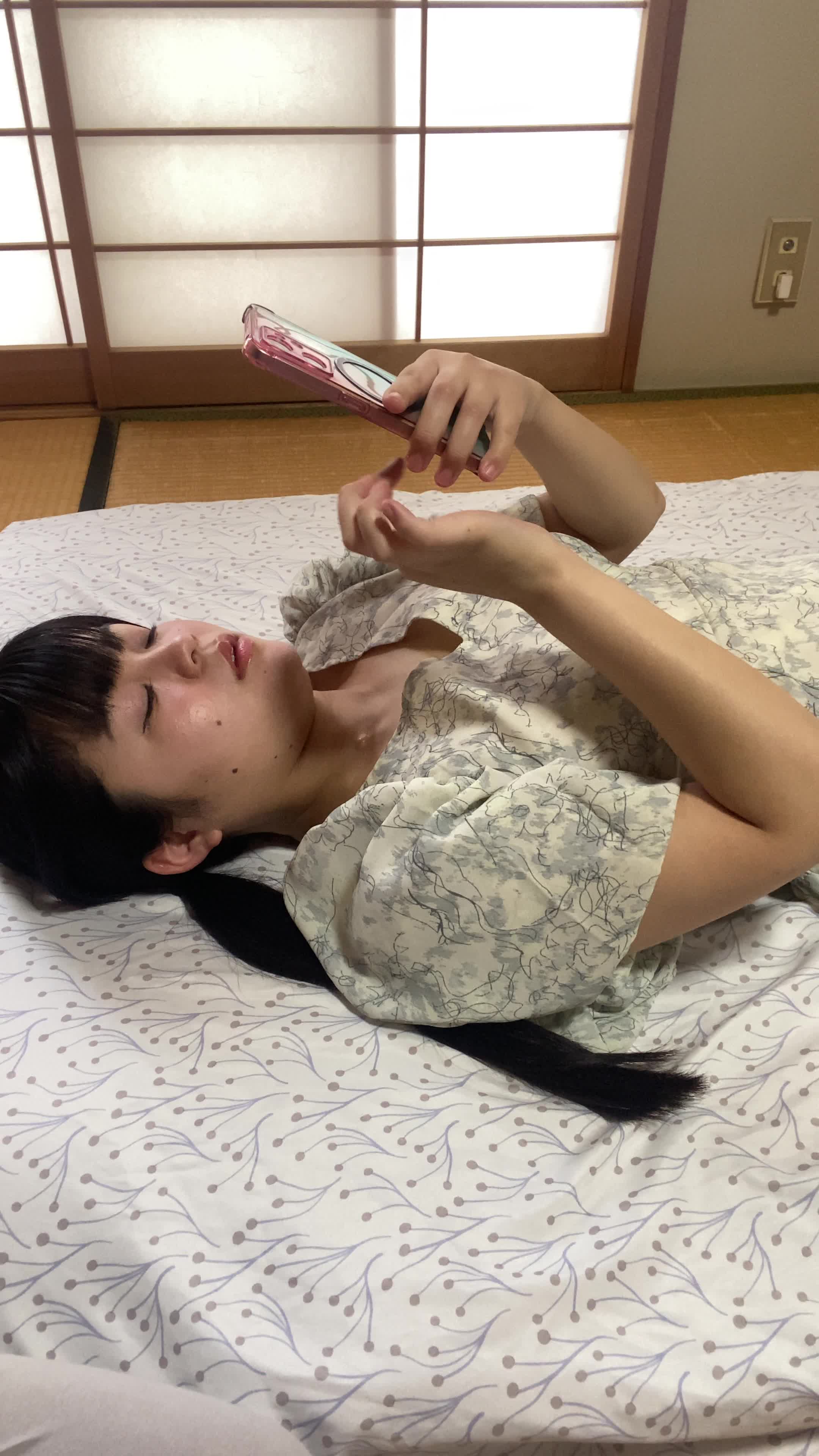 ベッドで横になり、「夜中に喉が渇いたとき、すぐに水があれば…」とスマホを見つめる姿