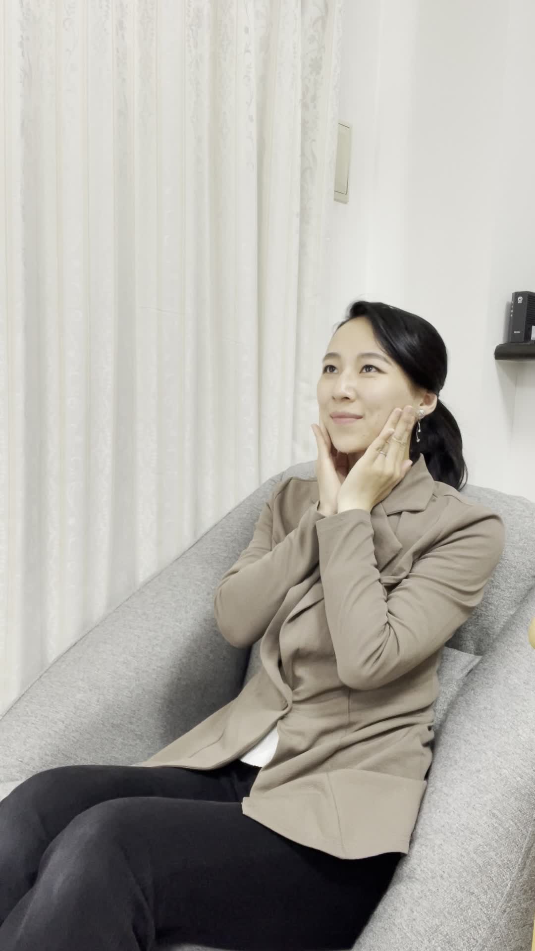 ソファで手を頬に当て、「小顔になったら髪型も変えられるかも」と考える仕草