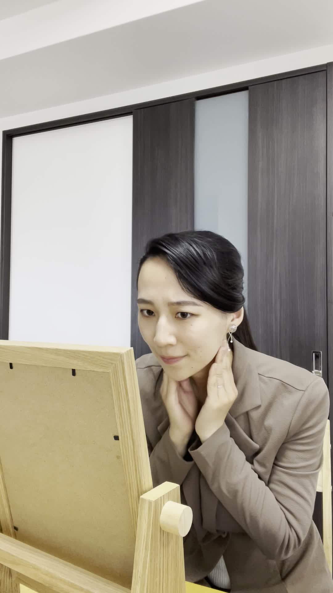 テーブルで鏡を覗き込み、「このたるみ、無くせるかな？」とじっと見つめる姿