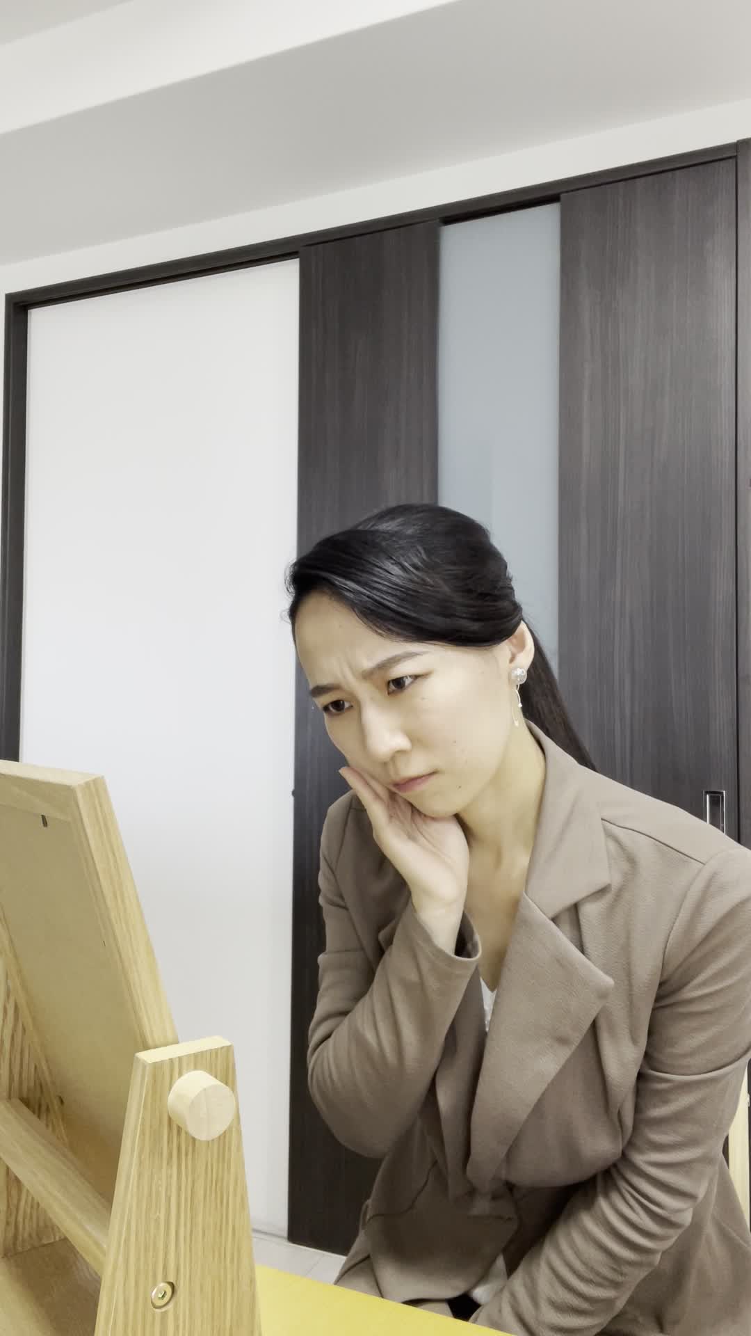 テーブルに手鏡を置いて、「本当に効果あるの？」と眉をひそめて考え込む動作