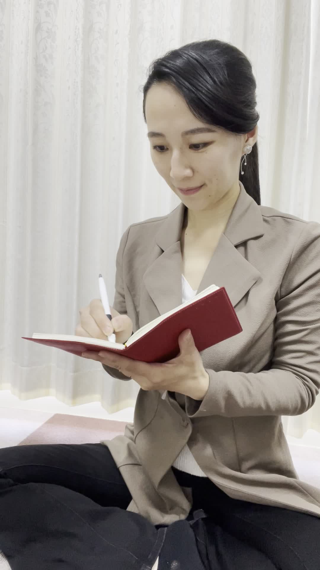 床に座り込み、メモ帳に「GOAL」を書き出しながらうなずく動作