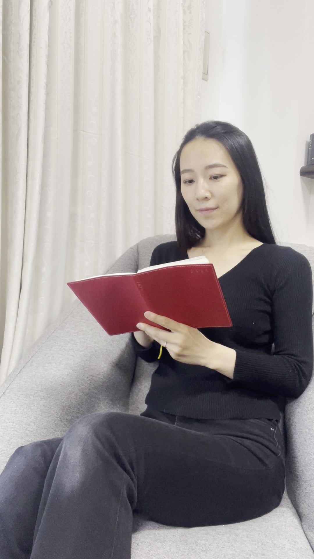 ソファでリラックスしながら、手帳に未来の目標を書き込む動作