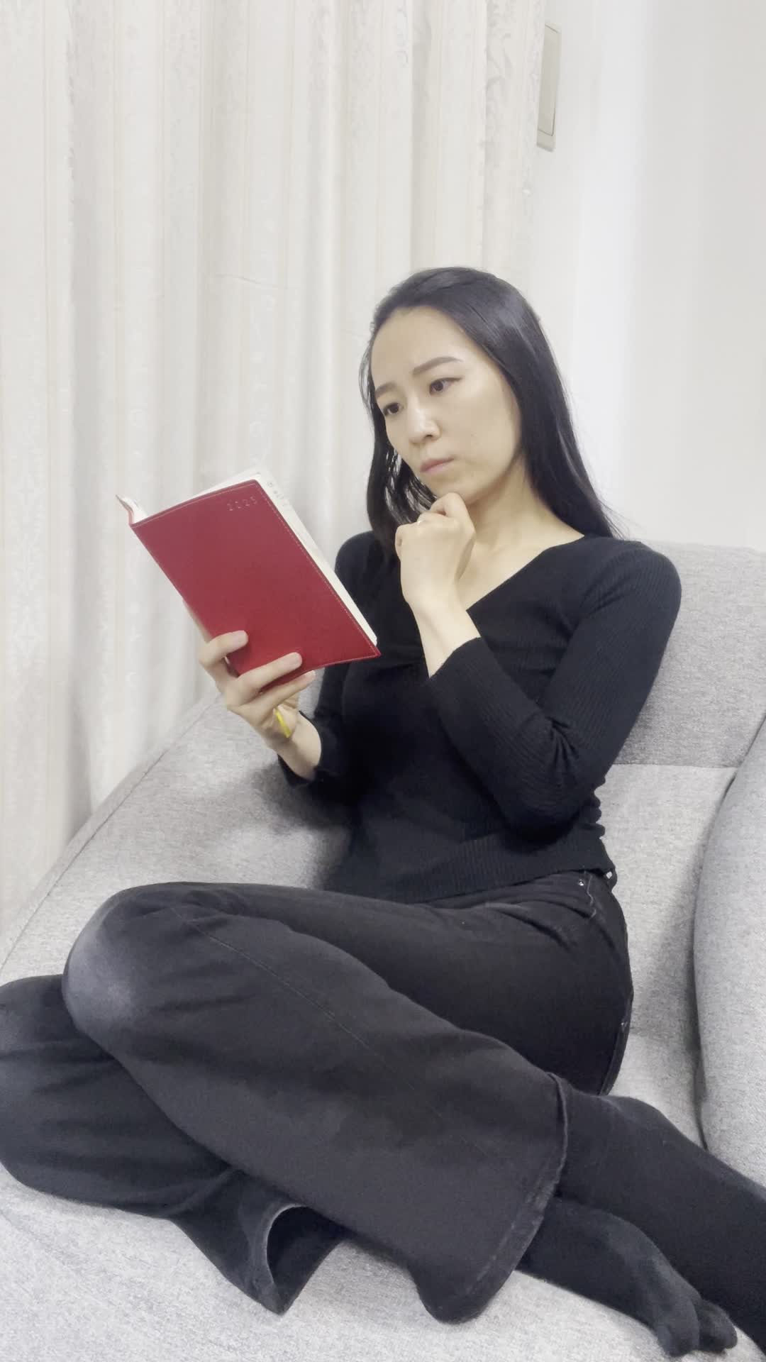 ソファに横座りして、手帳に目を通しながら次を考える表情