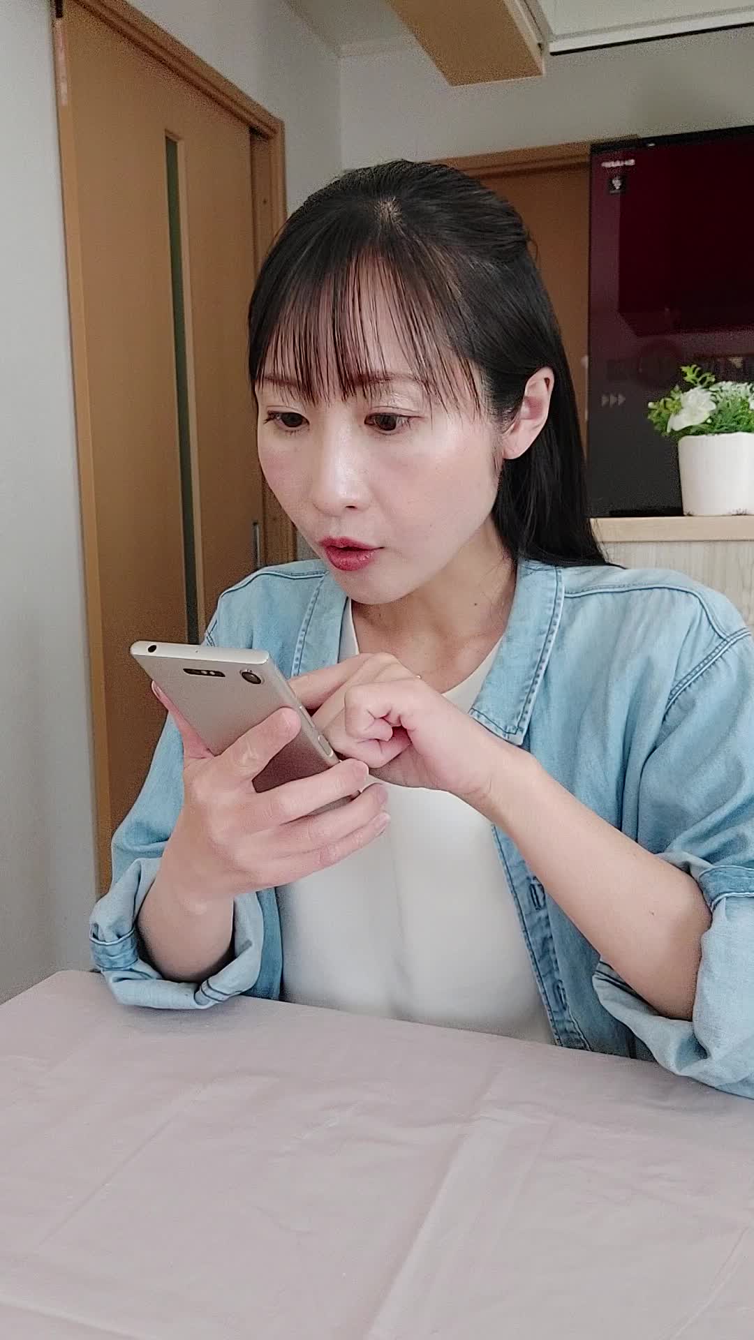 椅子に座り、スマホでカートの中身を確認しながら「これ全部買おうかな？」と悩む表情