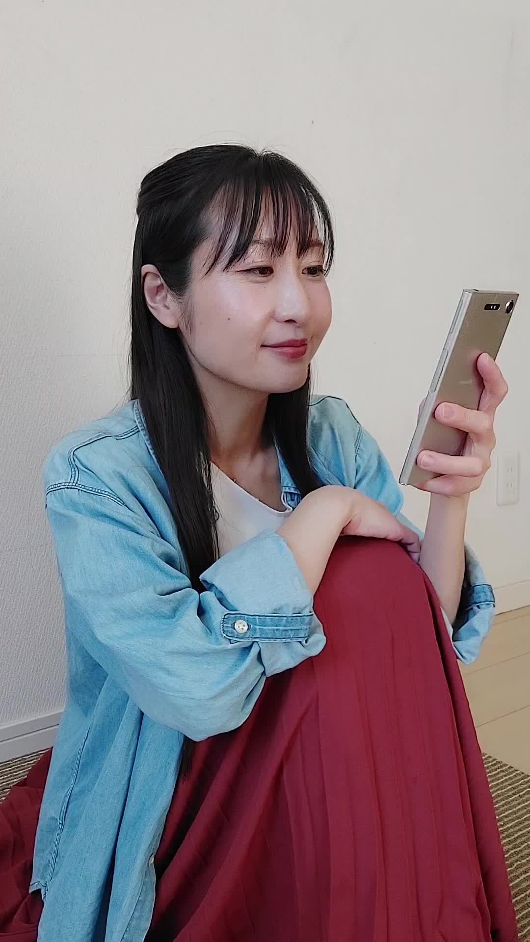 床に座り込み、スマホで商品画像を見て「このデザイン素敵！」と微笑む仕草