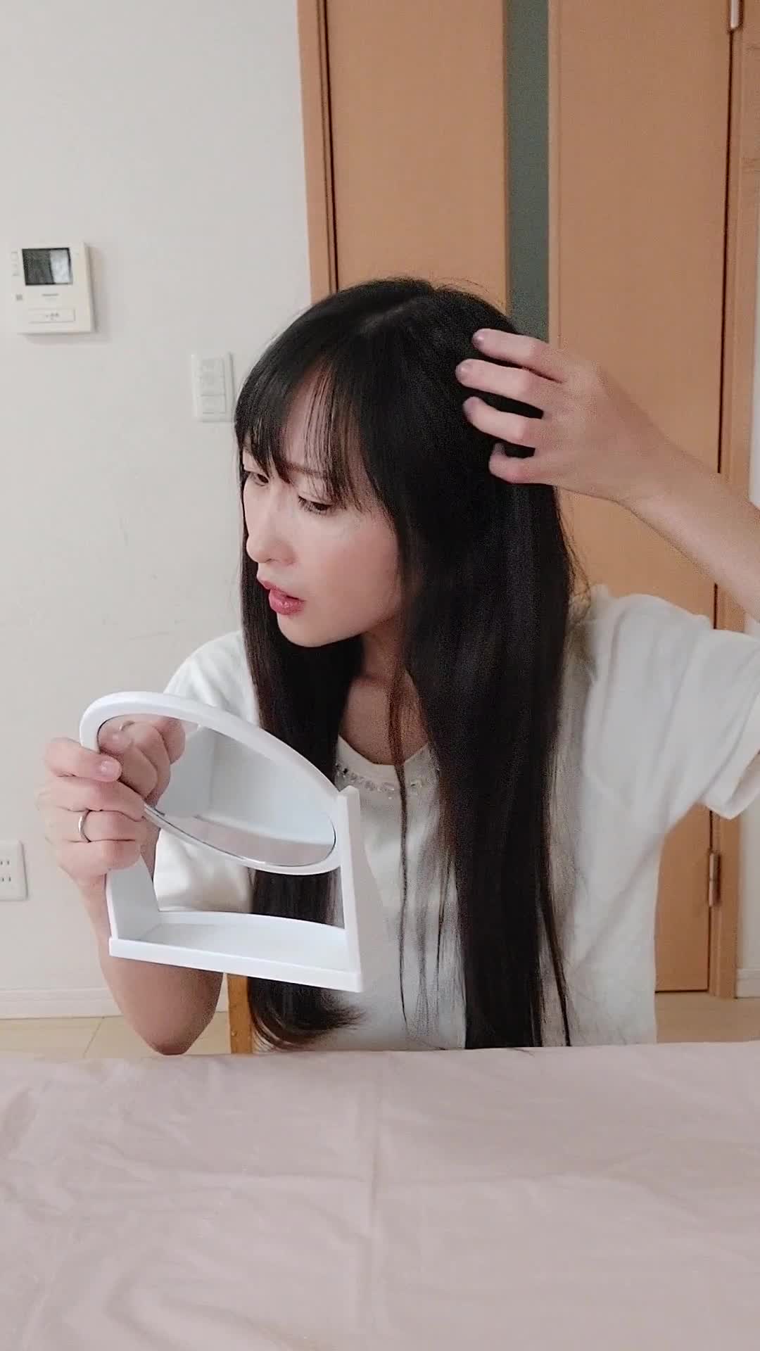 椅子に座り、鏡を見ながら白髪を気にして「どうにかならないかな」と悩む表情