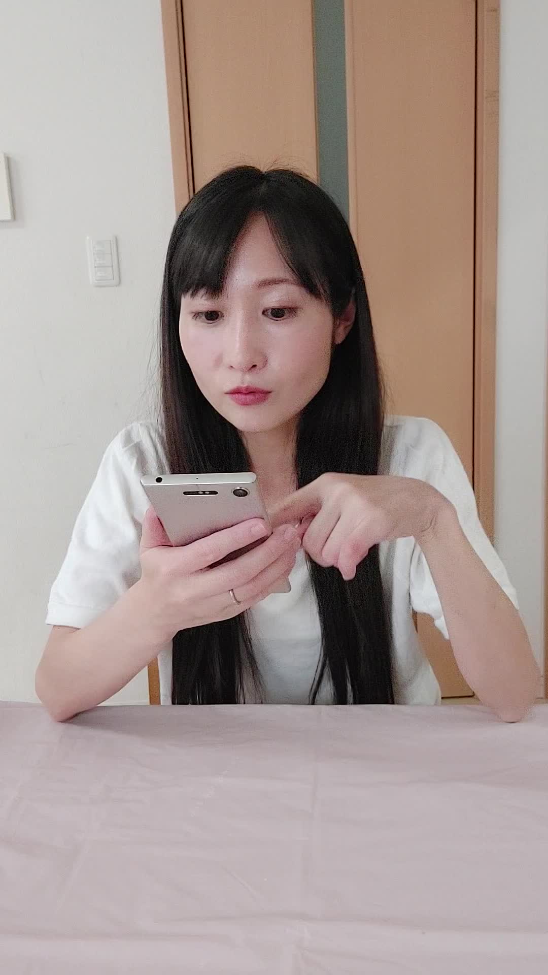 椅子に腰掛け、スマホの画面を見て「白髪ケアの口コミを読んで納得する」表情