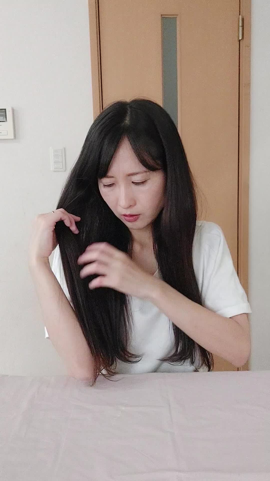 テーブルで髪を手に取り、「白髪部分をどうケアしよう」と計画する真剣な表情