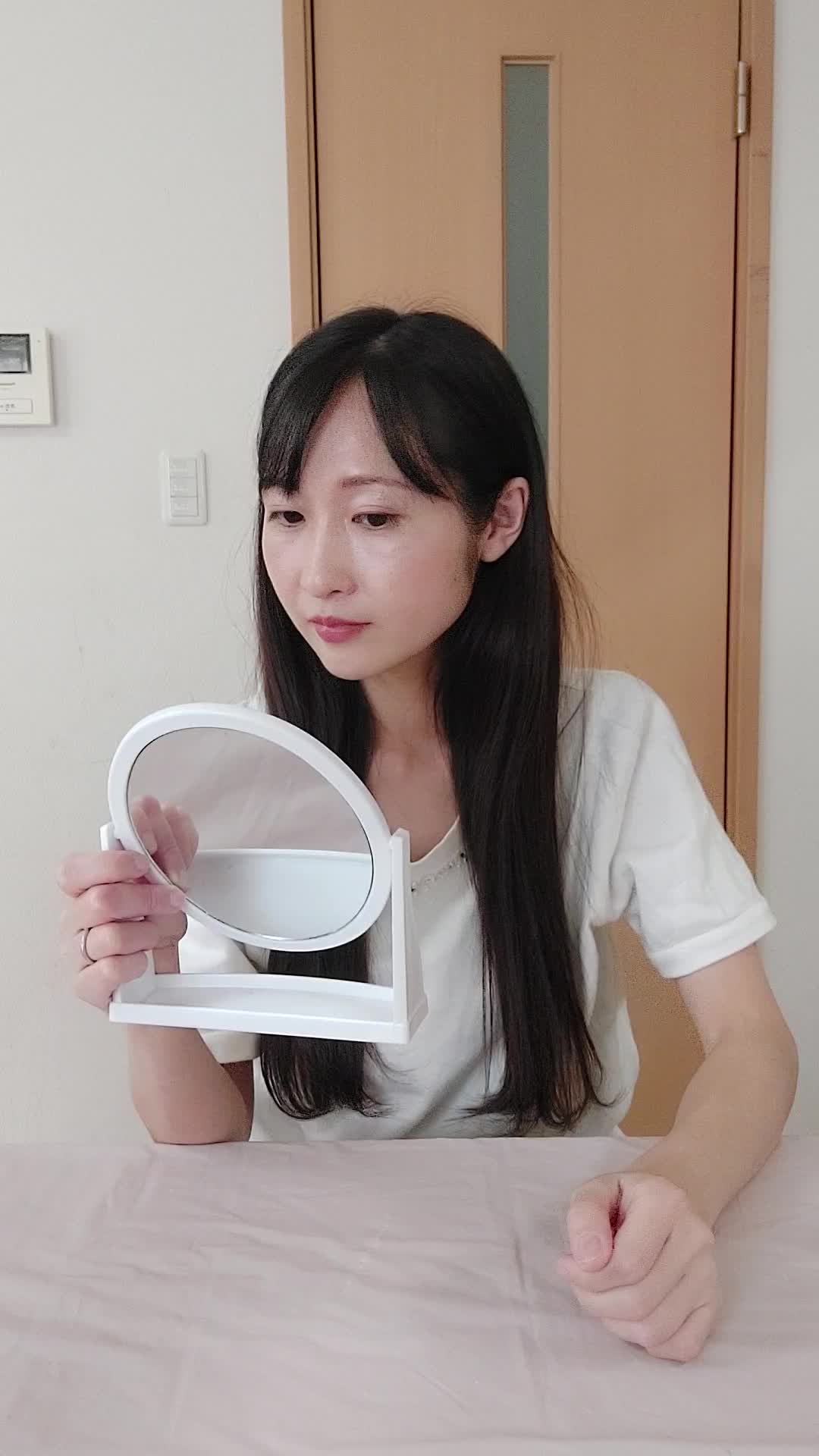 テーブルで鏡を手に取り、「白髪の変化をじっくり確認する」動作