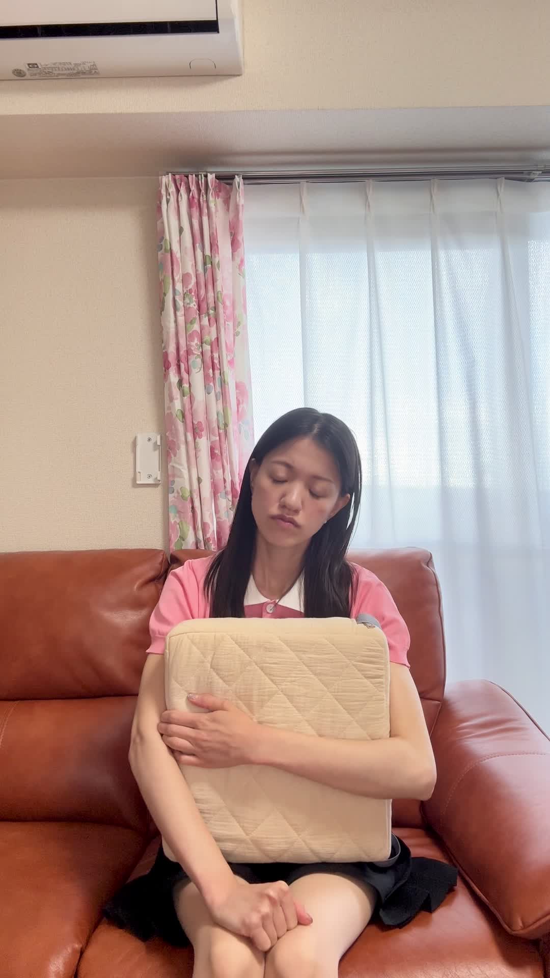 ソファでクッションを抱え、「これで匂いが改善するかな？」と悩む真剣な表情