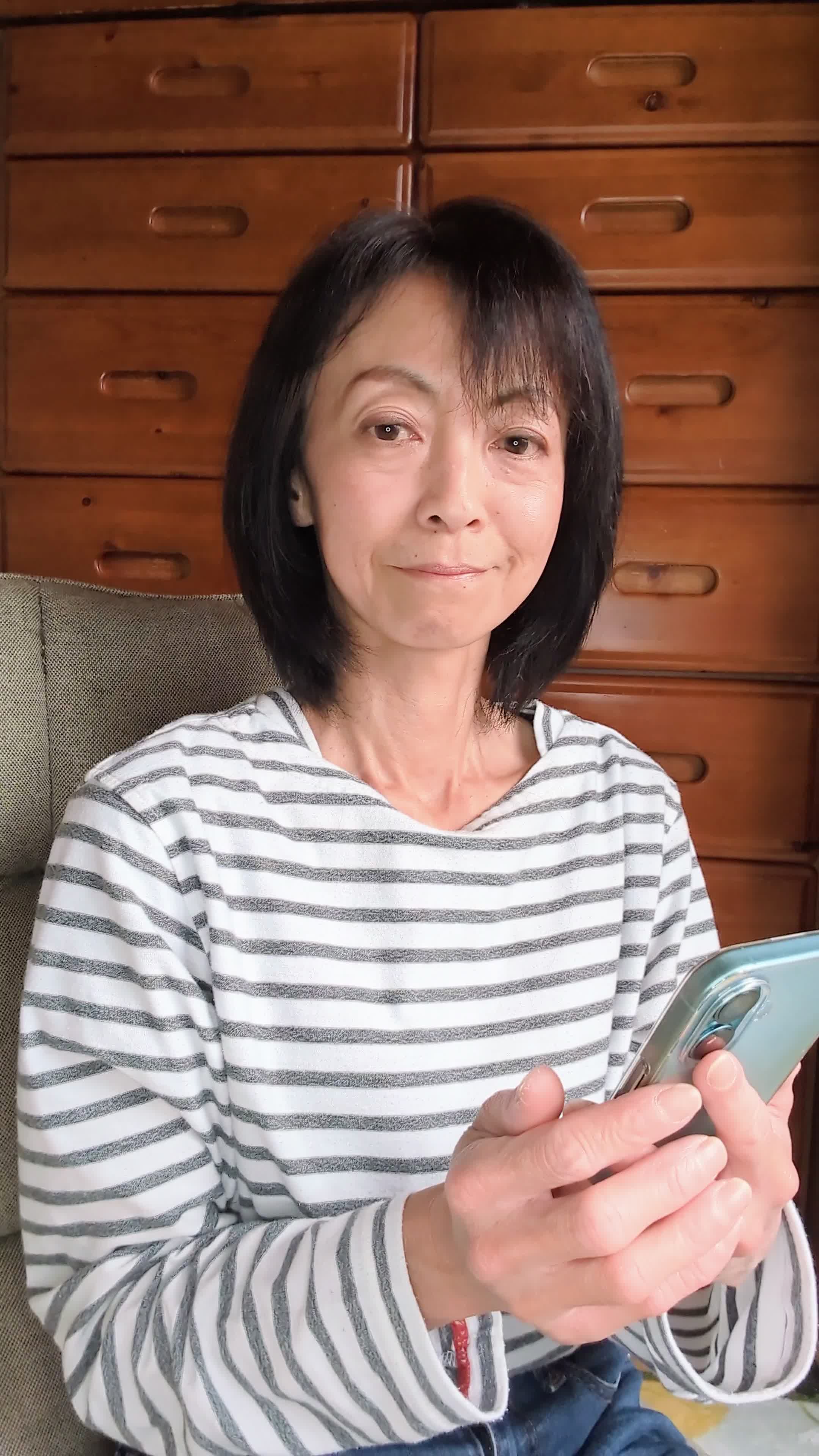 ソファでスマホを操作しながら、「次の休憩時間までに何を観るか選ぼう」と考える様子