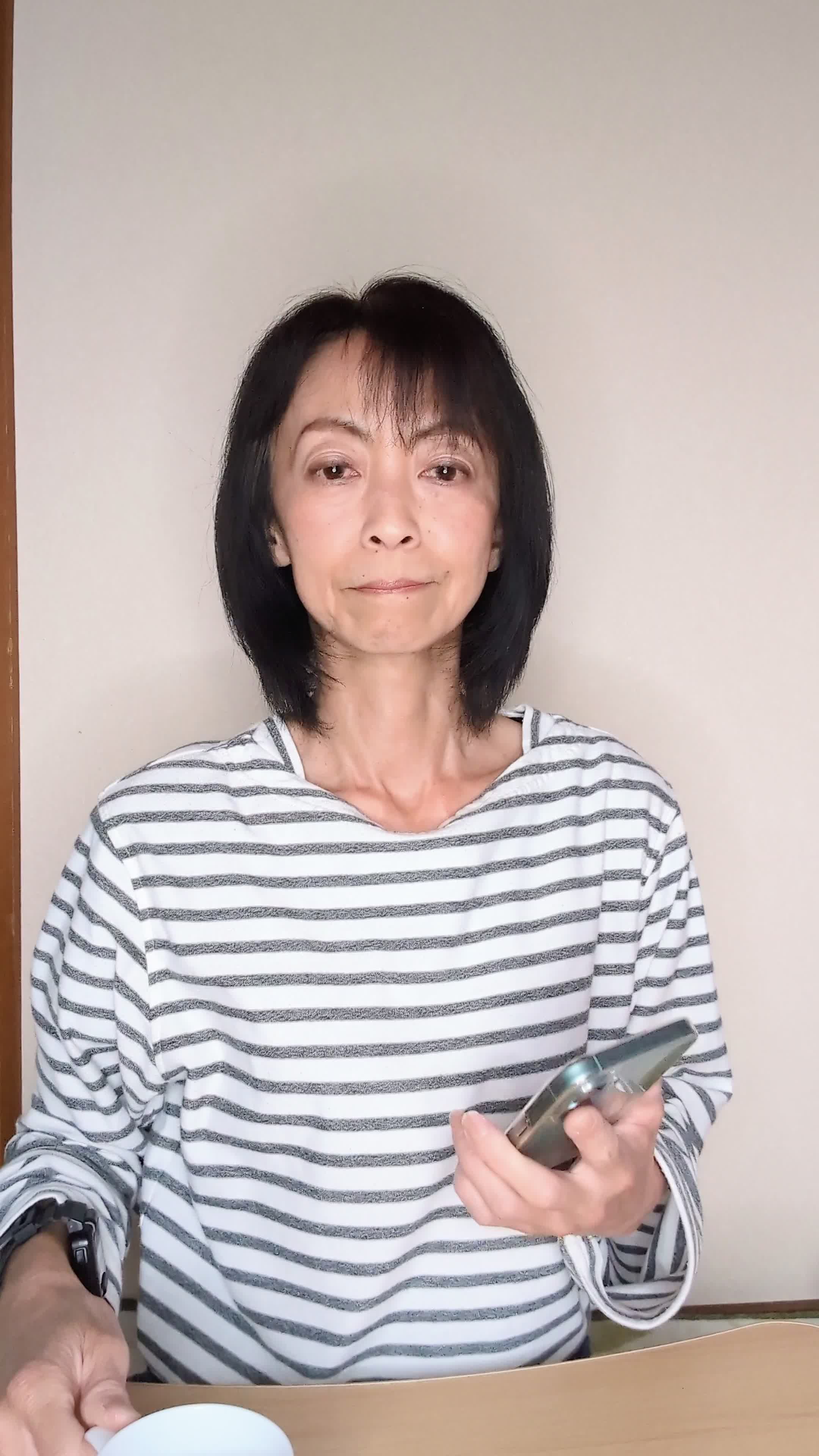 テーブルでコップを手に、「観たい作品が多すぎて迷う」と真剣に考える動作