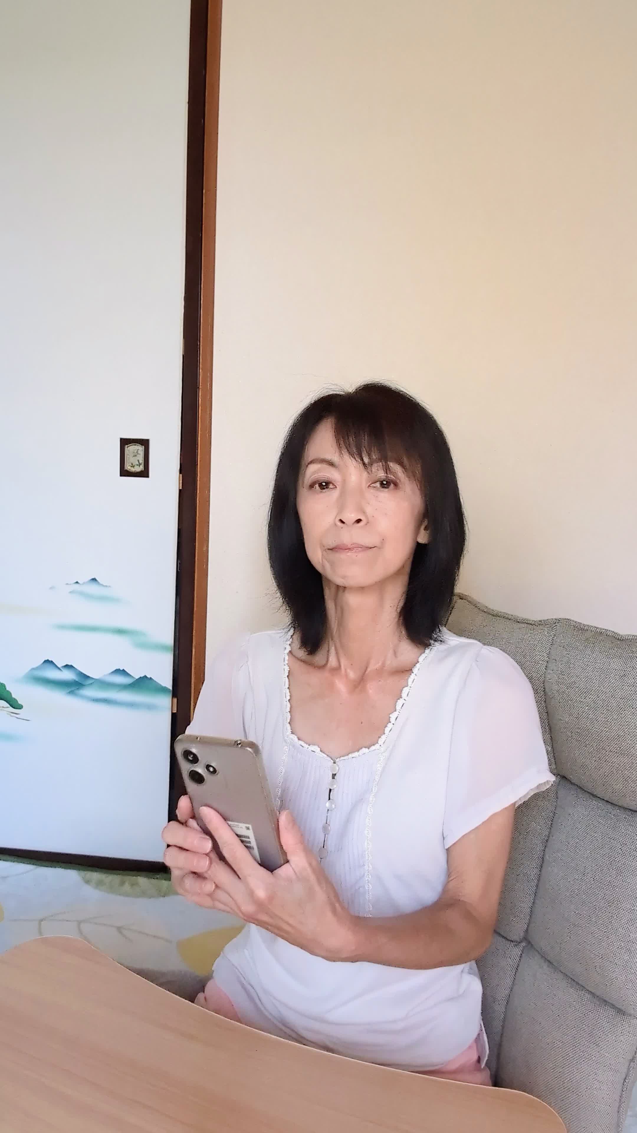 テーブルでスマホに検索結果をスクロールしながら、「どの矯正方法がいいのかな？」と考える仕草