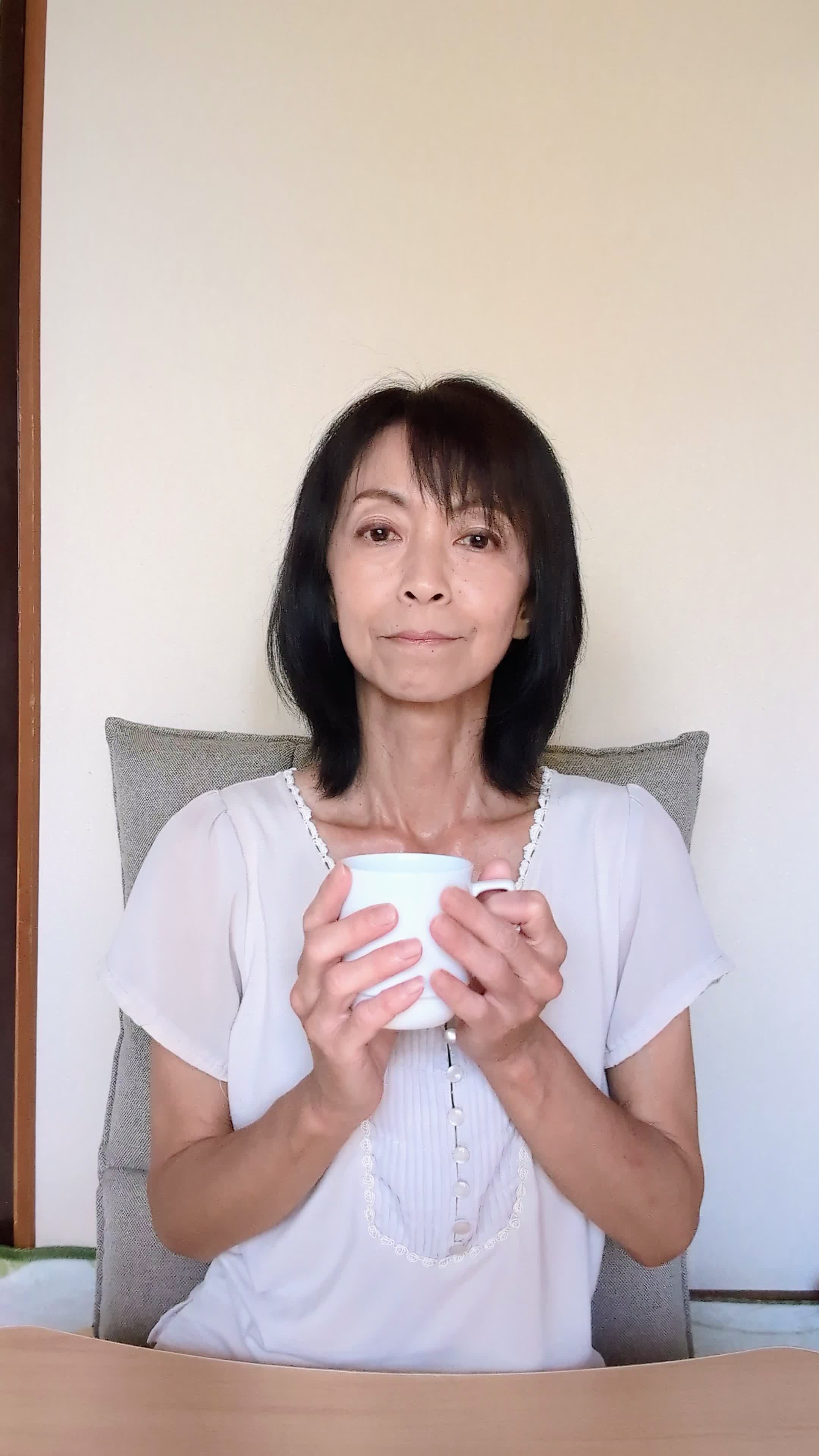 テーブルでカップを手に取り、「矯正中でも食べやすいメニュー」を考える表情