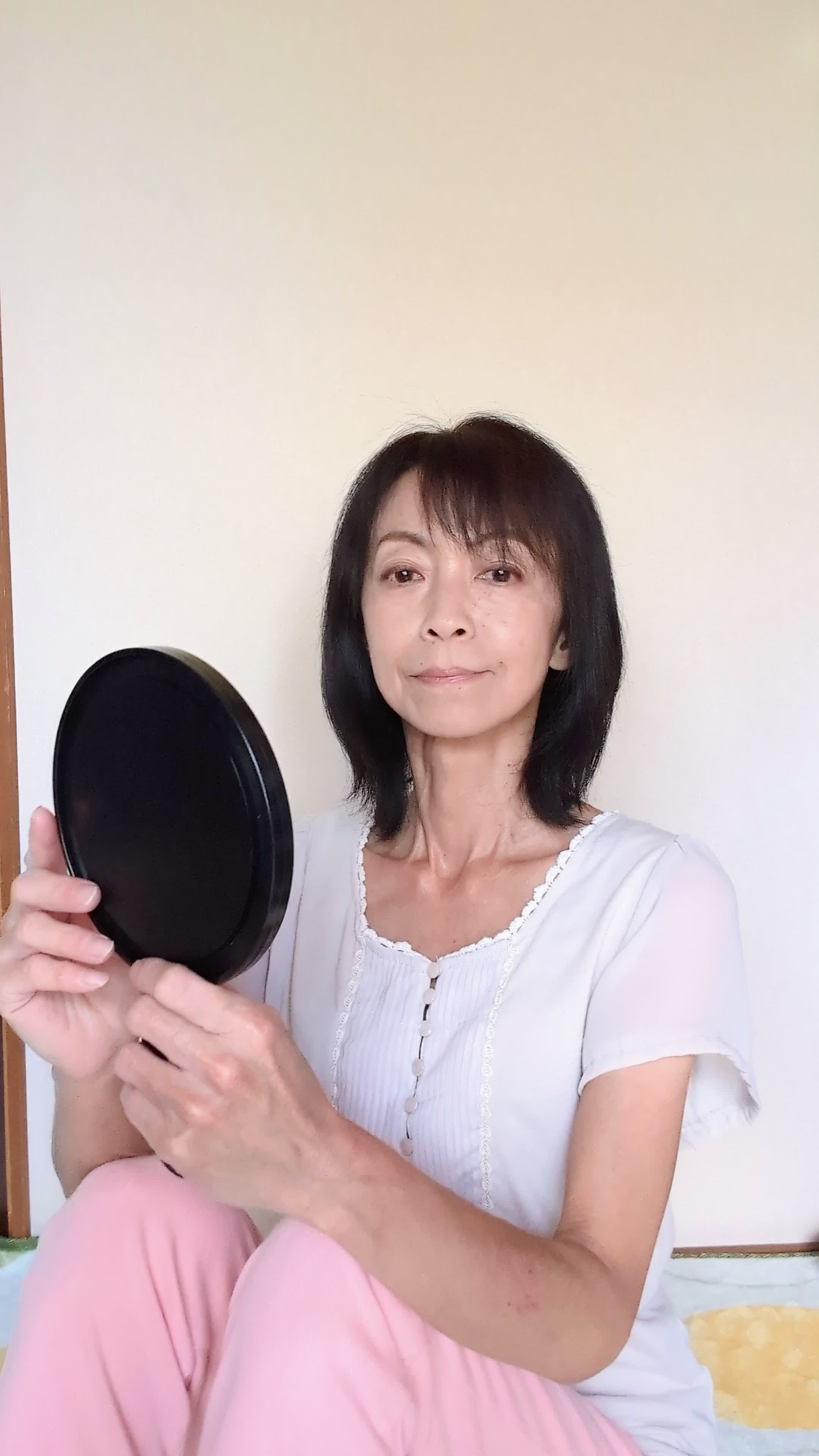 床に座り込み、手鏡で自分の歯をじっくり観察し、「これが変わるかな？」と期待する表情