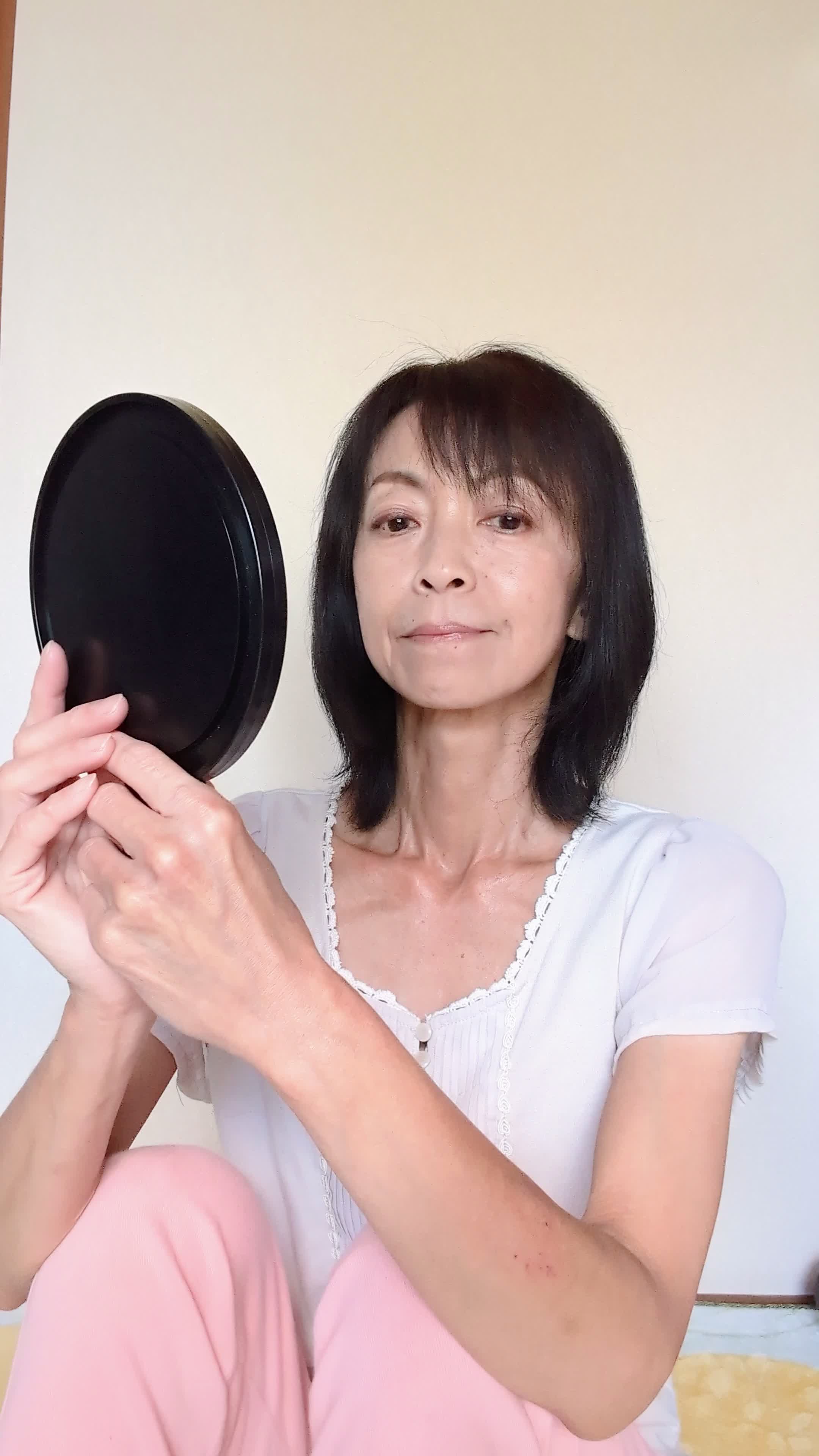 床で鏡を見つめ、「矯正器具を目立たせない工夫」を考える姿