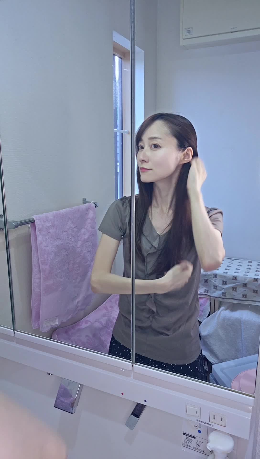 鏡に向かって微笑み、髪の状態をチェックしている姿を見せる