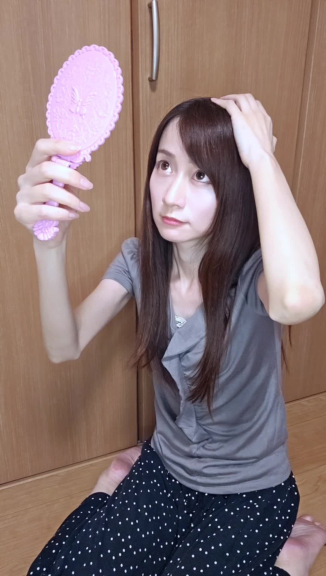 床に膝をつき、鏡を持って頭頂部を確認する仕草をする