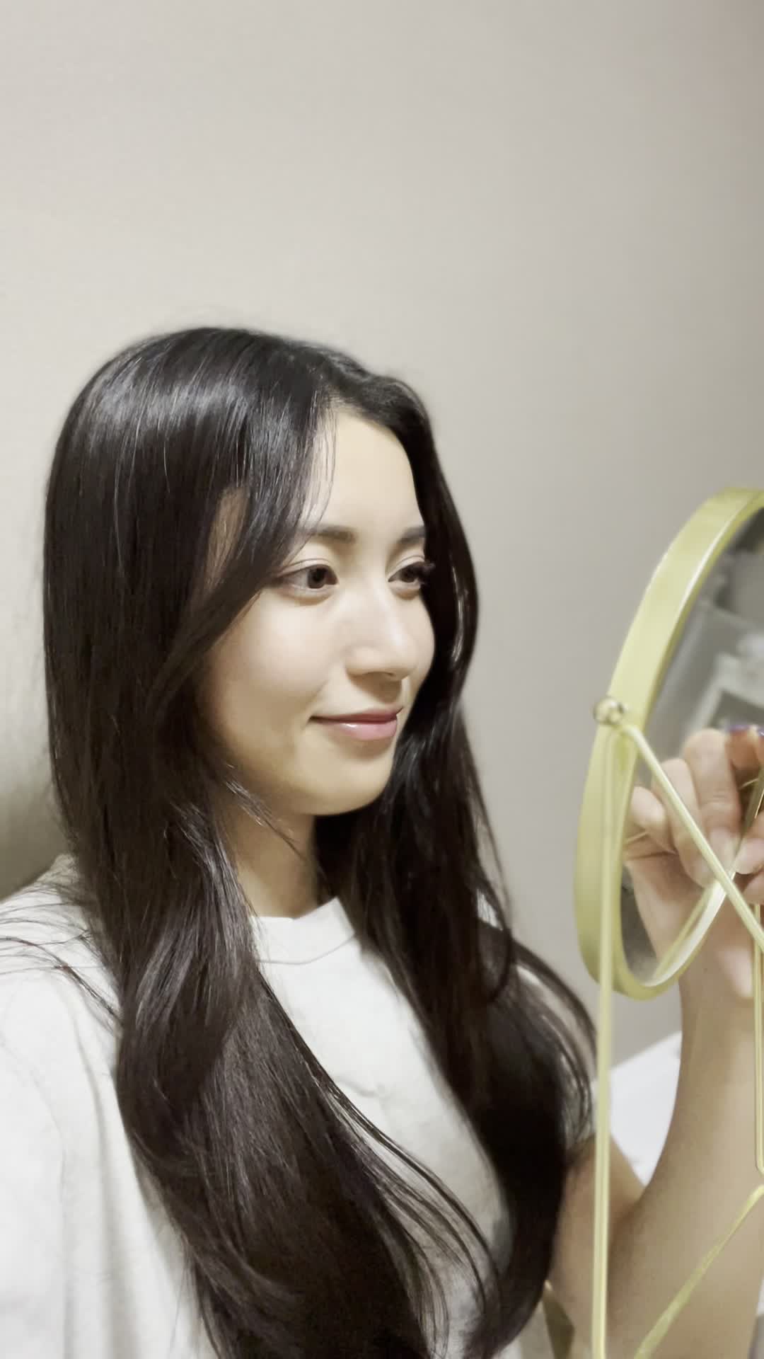 鏡に向かって微笑み、髪の状態をチェックしている姿を見せる