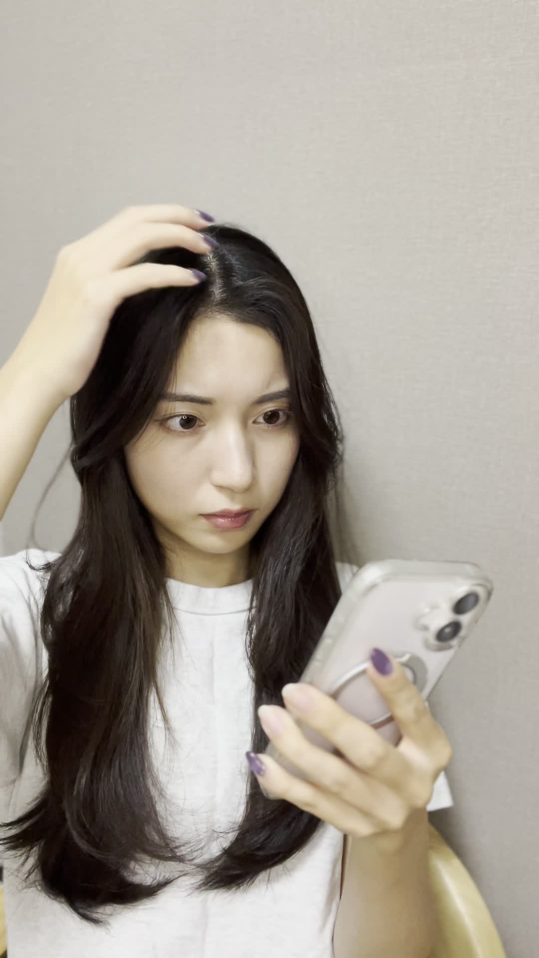 スマホを片手で持ち、もう片手で頭を触りながら考え込む