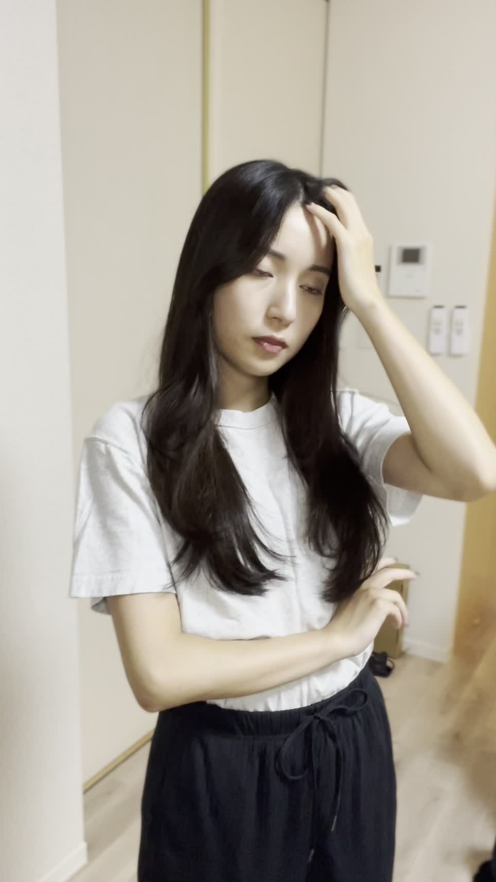 髪を気にしながらリビングで立ち止まり、少し困った表情を浮かべる