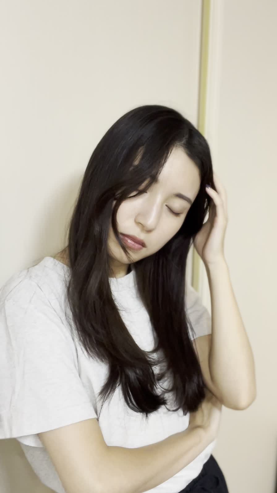 壁に寄りかかり、頭に手を当てて考え込む仕草をする