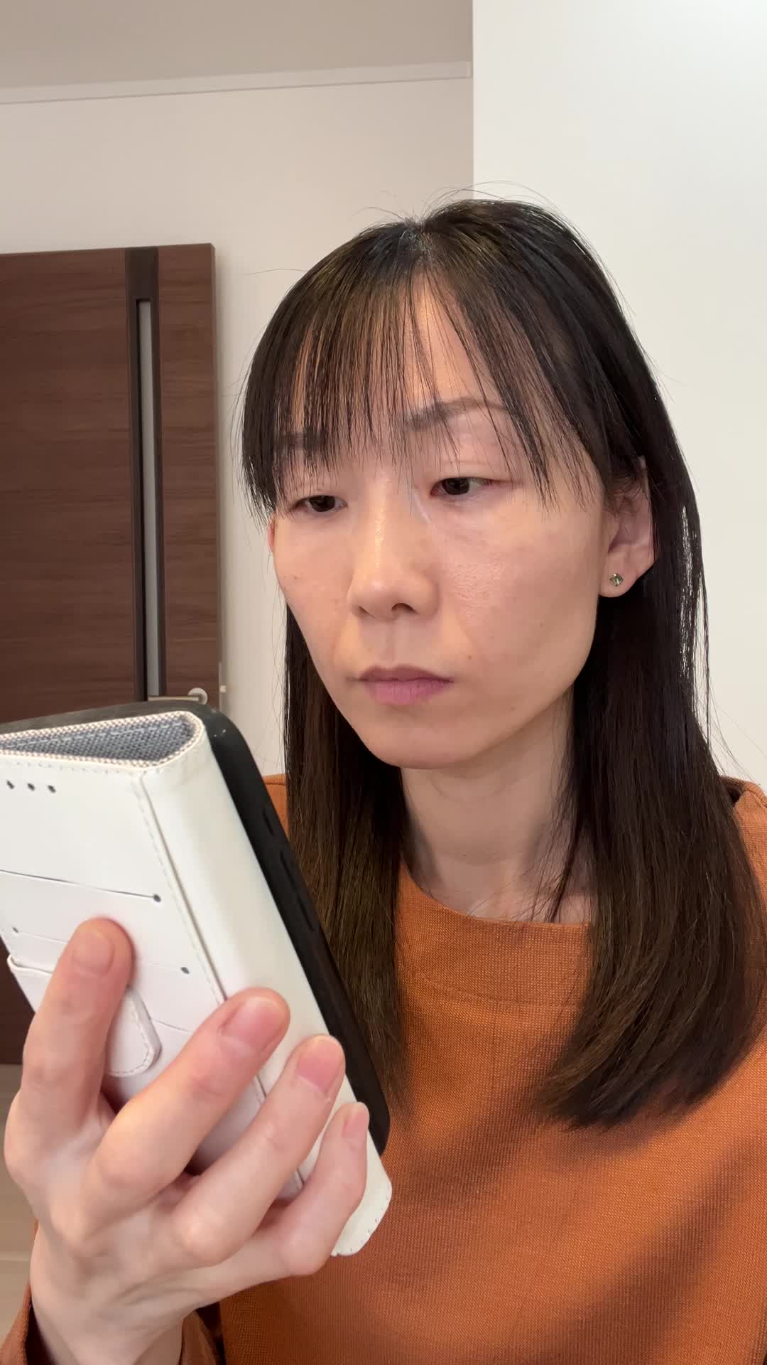 スマホを片手で持ち、もう片手で頭を触りながら考え込む