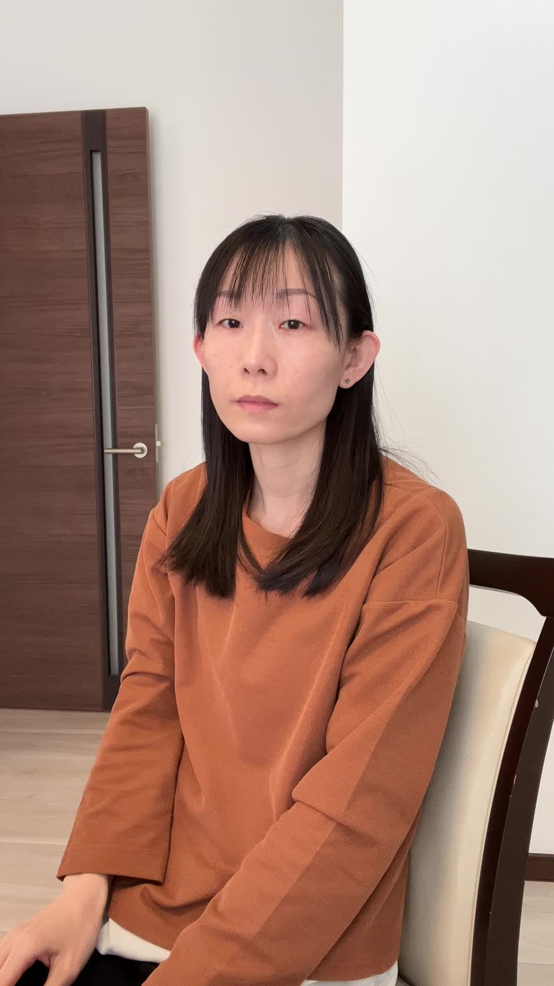 椅子に腰掛け、両手で顔を覆い、悩んでいる様子を表現する