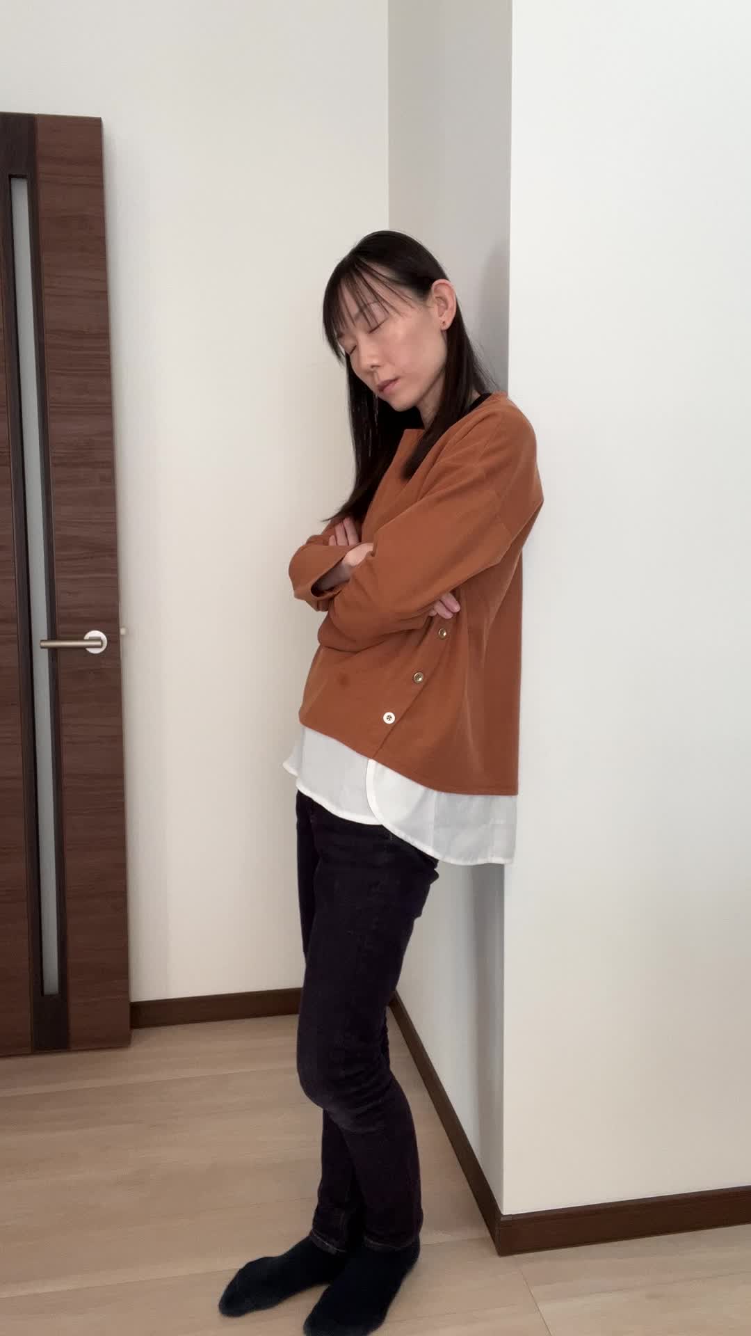 壁に背を預けて静かに目を閉じ、悩みを抱えている仕草をする