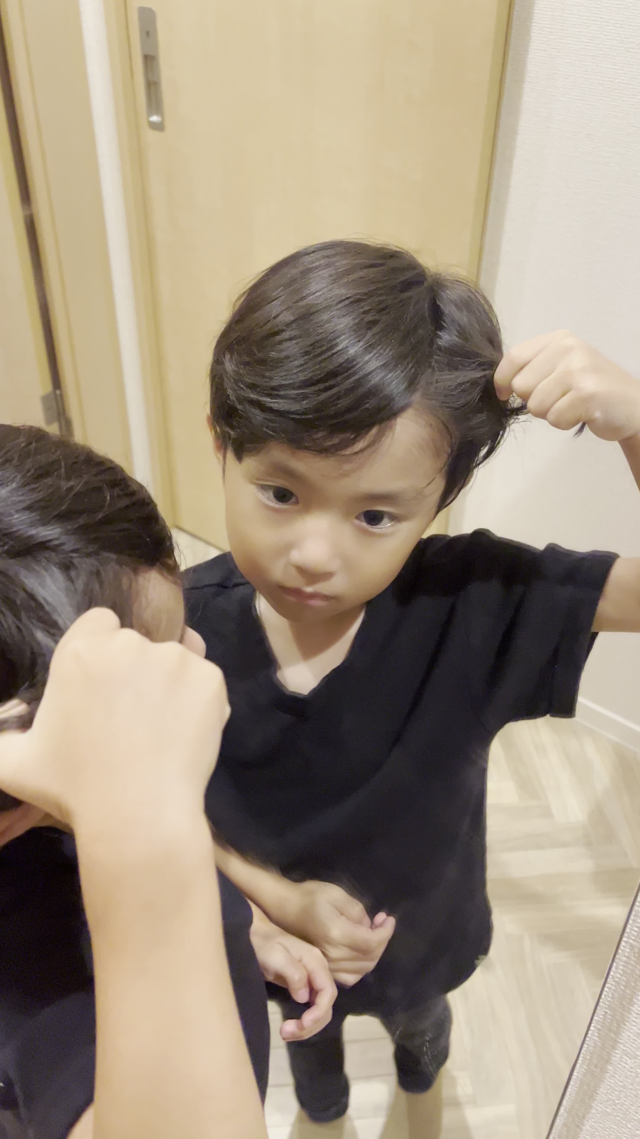 鏡を見つめながら、髪を軽く引っ張り状態を確認する仕草をする