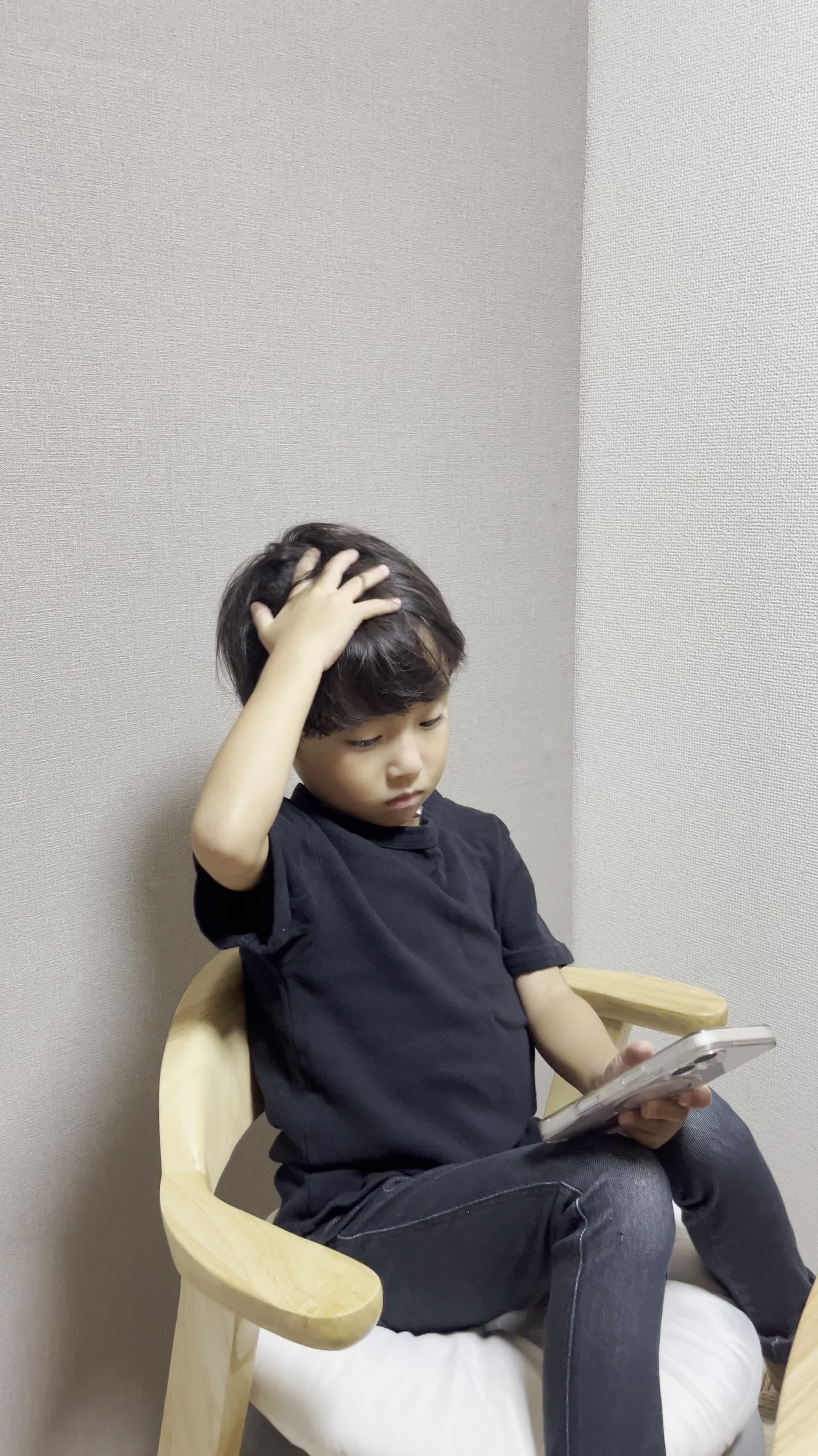 スマホを片手で持ち、もう片手で頭を触りながら考え込む