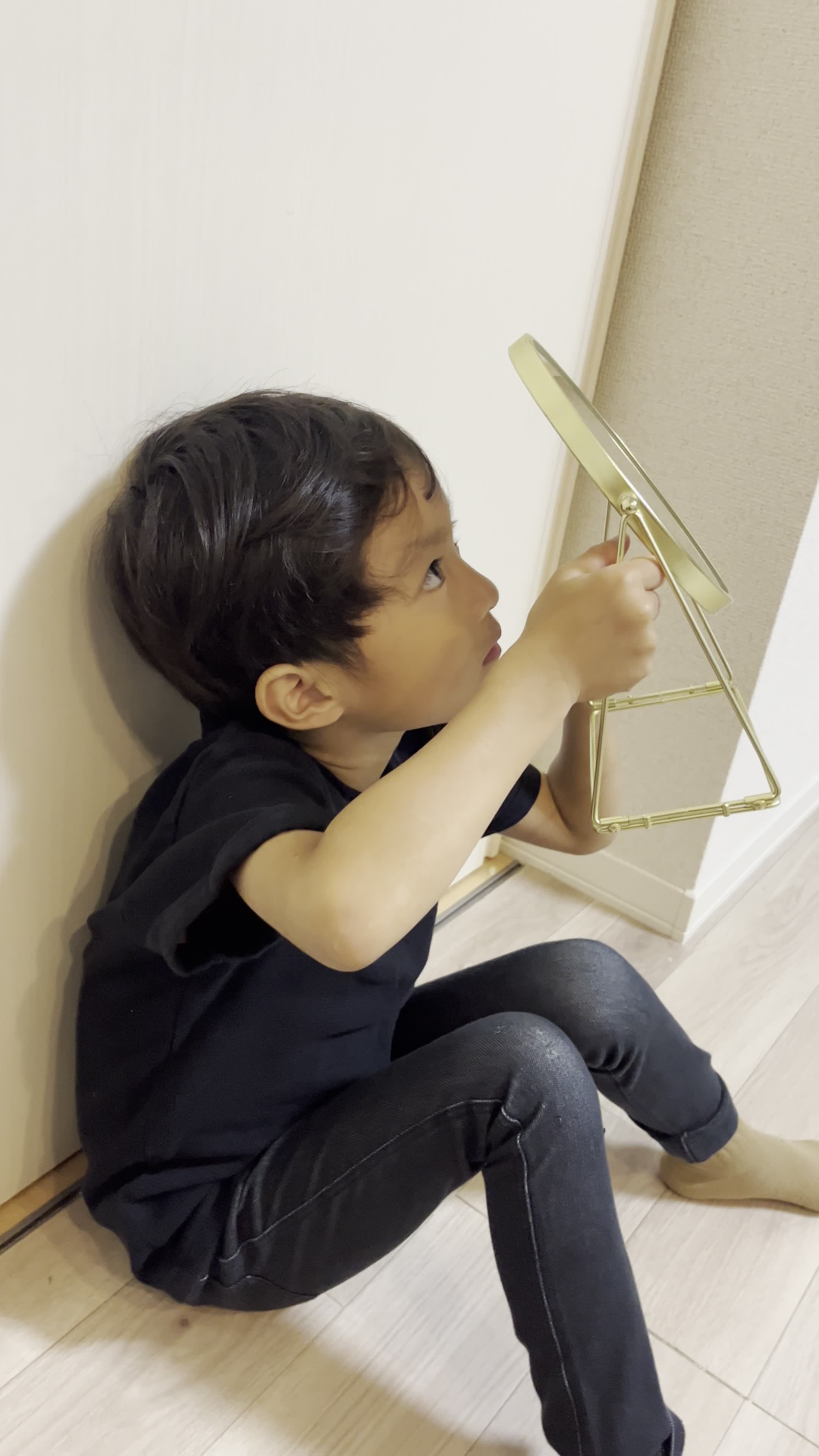 床に膝をつき、鏡を持って頭頂部を確認する仕草をする