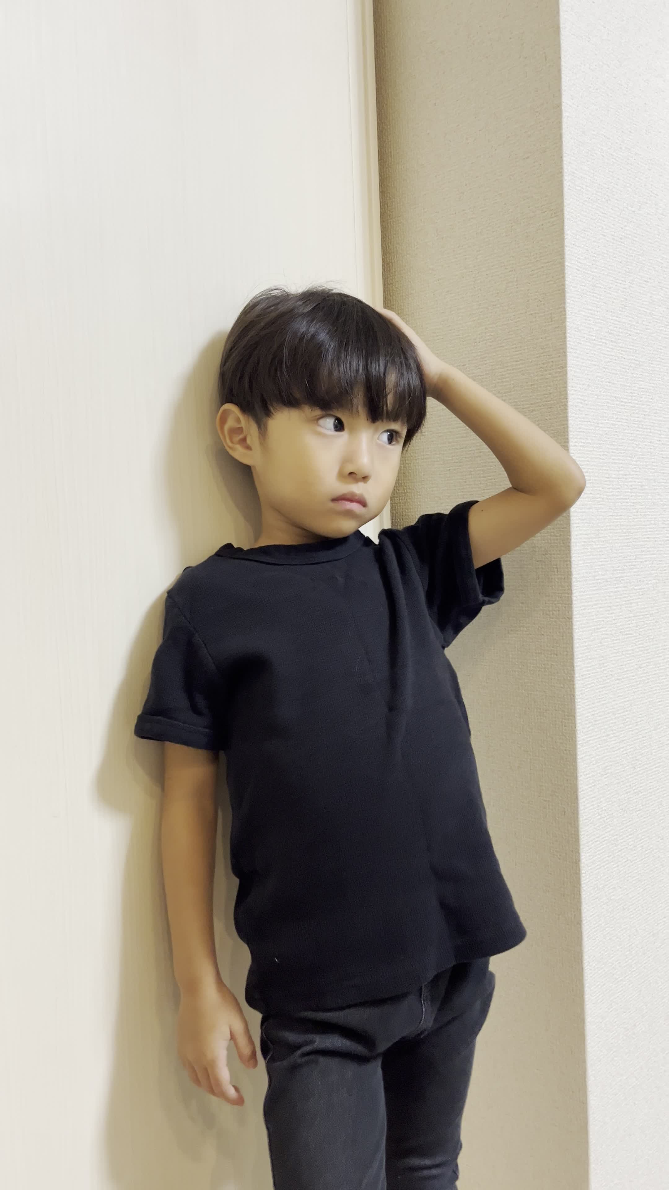 壁に寄りかかり、頭に手を当てて考え込む仕草をする