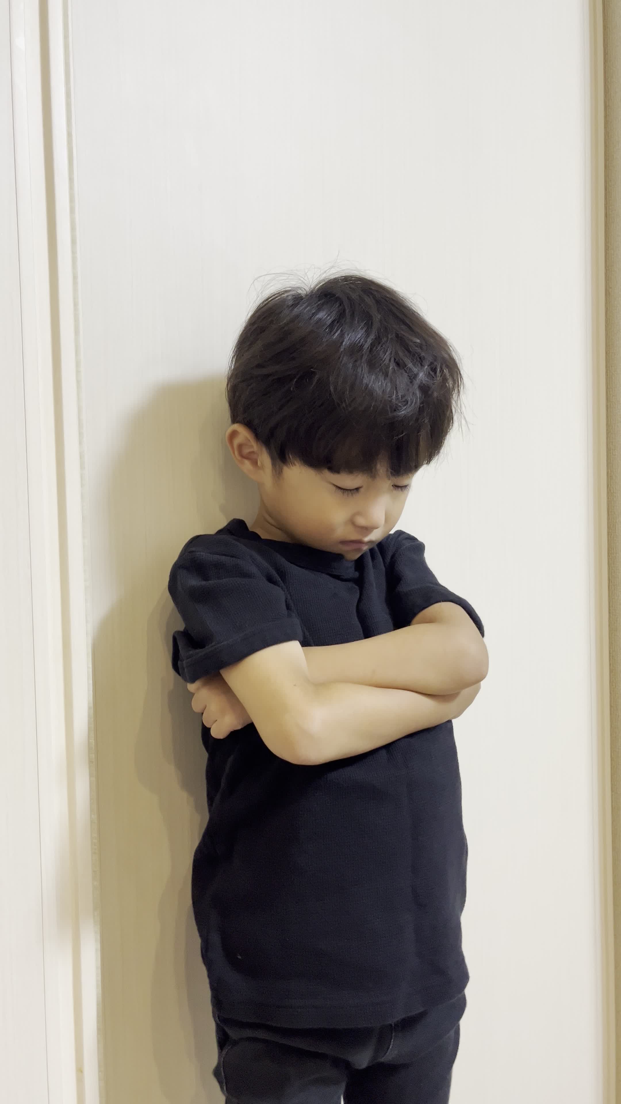 壁に背を預けて静かに目を閉じ、悩みを抱えている仕草をする