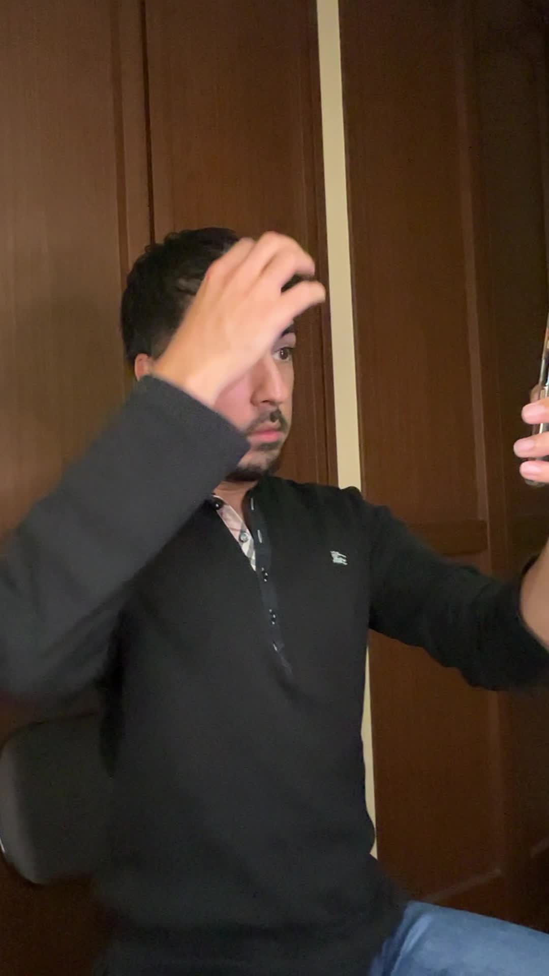 スマホを見つめながら、髪を軽く引っ張り状態を確認する仕草をする